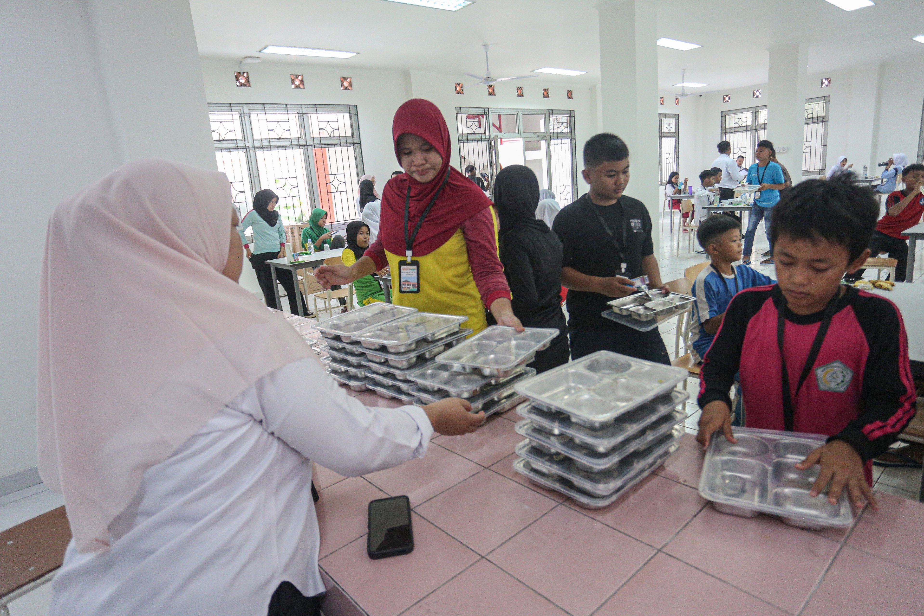 Sejumlah siswa merapihkan tempat makan setelah digunakan saat mengikuti kegiatan Masa Pengenalan Lingkungan Sekolah (MPLS) di Sekolah Rakyat Menengah Pertama 6, Sentra Handayani, Bambu Apus, Jakarta Timur, Senin (14/7/2025). Pemerintah resmi memulai program Sekolah Rakyat pada tahap pertama yang dirancang sebagai sekolah berasrama dan diperuntukkan bagi siswa dari keluarga berpenghasilan rendah di 100 titik lokasi yang tersebar di seluruh wilayah Indonesia.