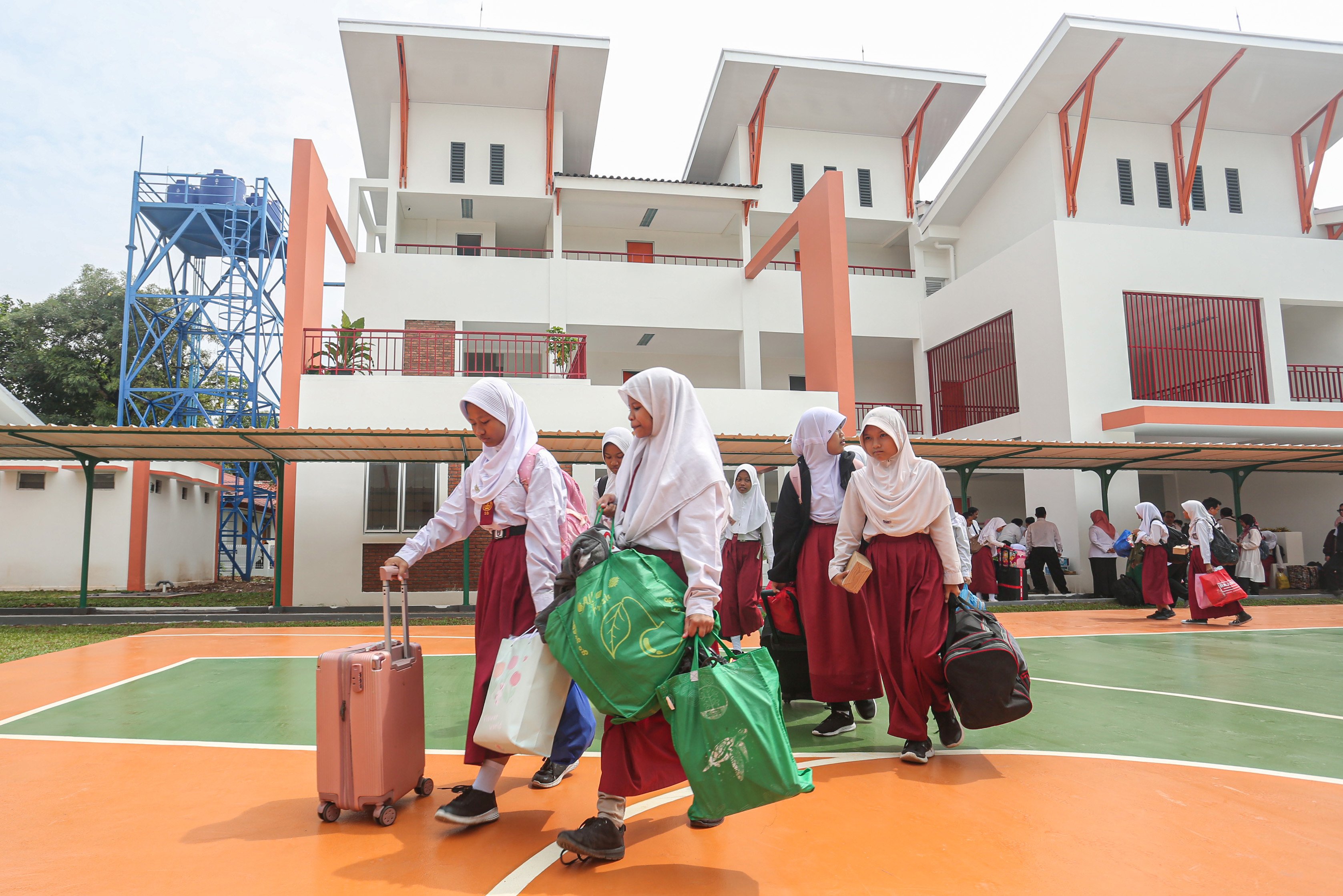Sejumlah siswa membawa barang untuk dipindahkan ke asrama saat mengikuti kegiatan Masa Pengenalan Lingkungan Sekolah (MPLS) di Sekolah Rakyat Menengah Pertama 6, Sentra Handayani, Bambu Apus, Jakarta Timur, Senin (14/7/2025). Pemerintah resmi memulai program Sekolah Rakyat pada tahap pertama yang dirancang sebagai sekolah berasrama dan diperuntukkan bagi siswa dari keluarga berpenghasilan rendah di 100 titik lokasi yang tersebar di seluruh wilayah Indonesia.