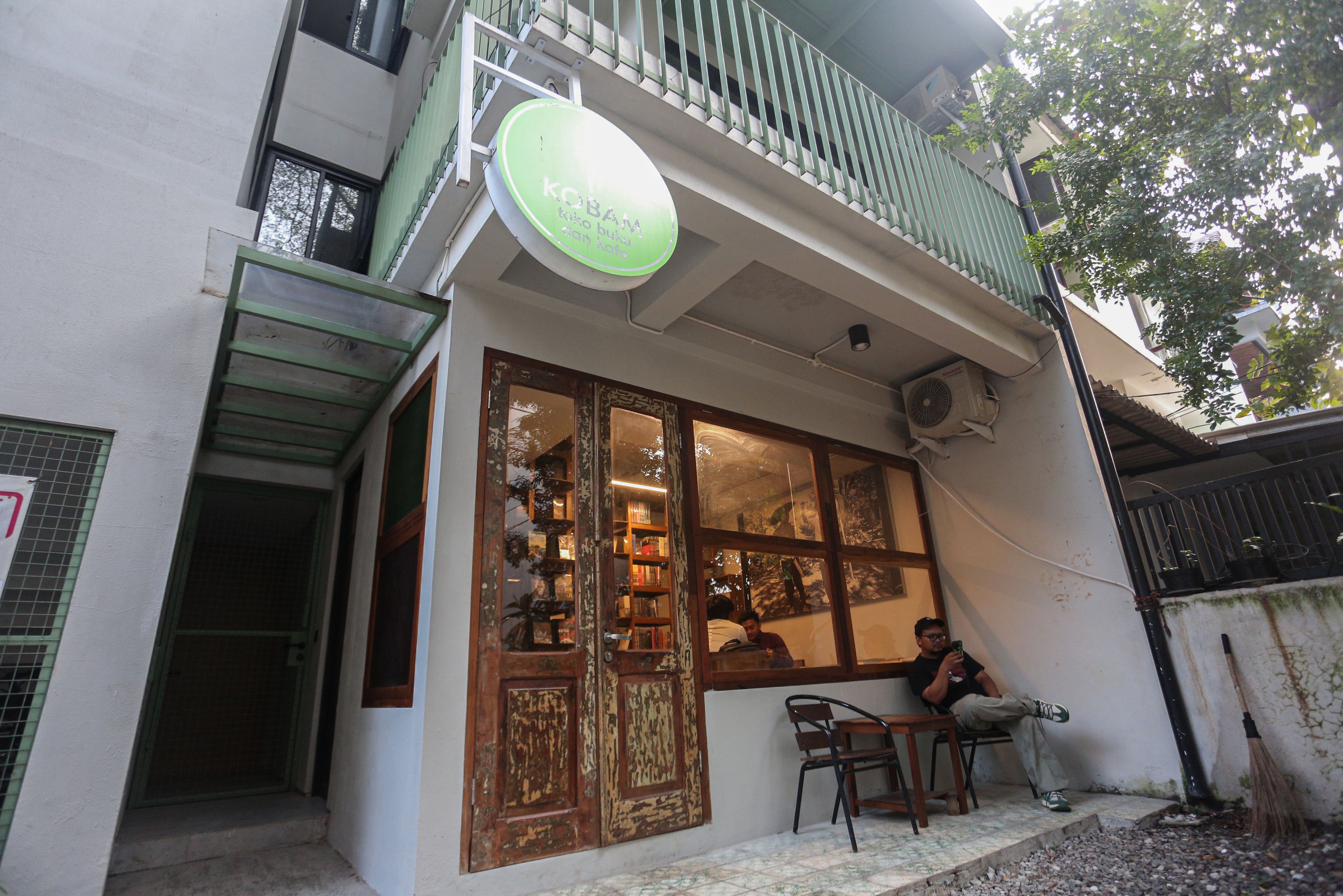 Pengunjung duduk di depan toko buku dan kafe yang berada di kawasan rumah flat di Jalan Rembang, Dukuh Atas, Menteng, Jakarta Pusat, Jumat (11/7/2025). Bangunan empat lantai dengan hunian sebanyak 10 unit dengan harga konstruksi berkisar Rp 300 juta hingga Rp 1 miliar per unitnya yang dikelola melalui skema koperasi ini menjadi salah satu solusi hunian terjangkau di pusat Kota Jakarta.