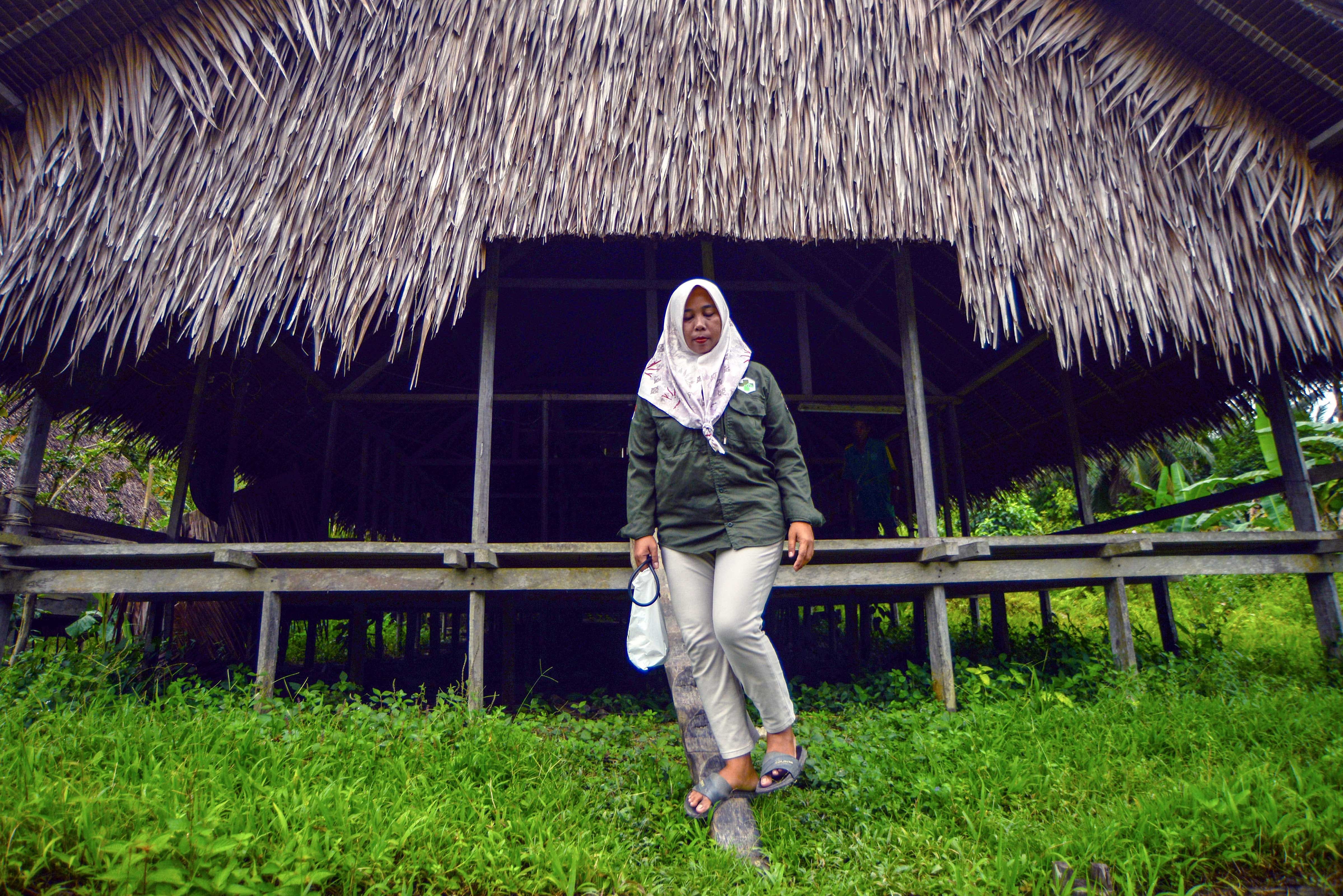 Bidan Ilen turun dari uma (rumah tradisional Mentawai) usai memeriksa kondisi kesehatan warga di Dusun Matektek, Desa Matotonan, Siberut Selatan, Mentawai, Sumatera Barat.