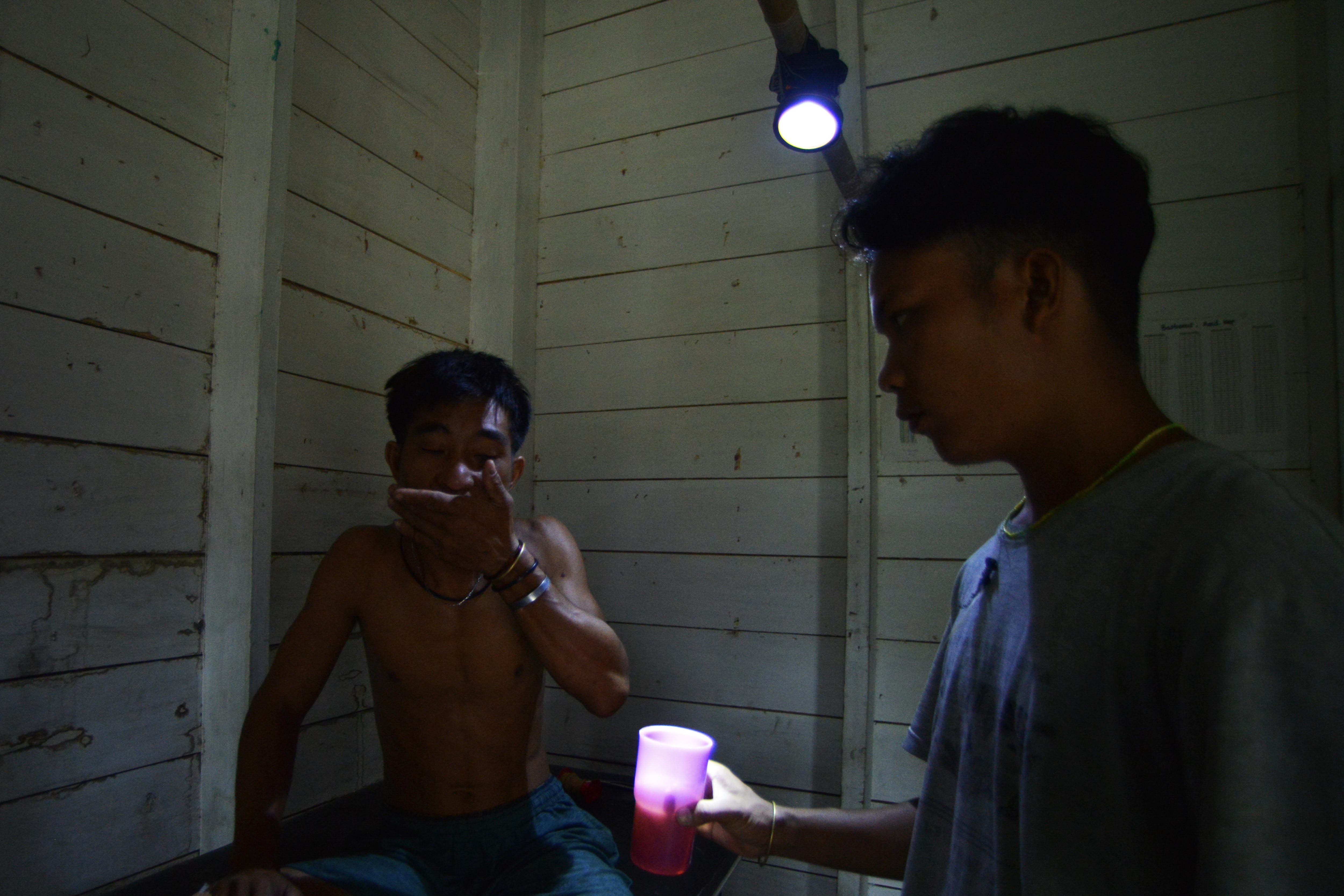 Seorang warga, Ajai Makmud meminum obat setelah ditangani bidan Ilen dengan bantuan lampu darurat, karena jari tangannya putus akibat terkena mesin pengolahan sagu di Desa Matotonan, Siberut Selatan, Mentawai, Sumatera Barat.