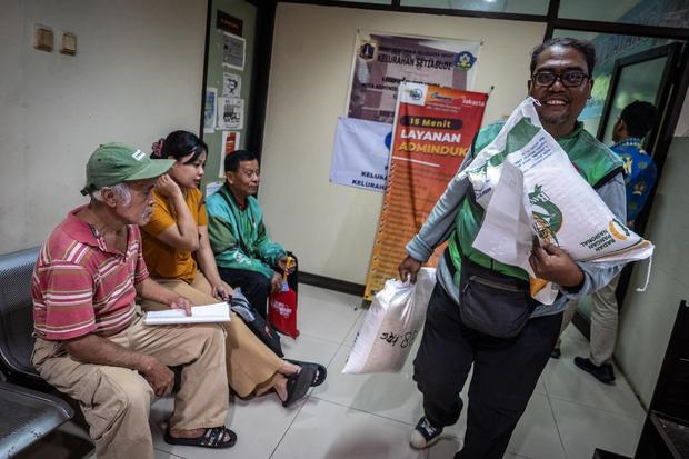 Warga berjalan keluar usai menerima beras saat penyaluran perdana bantuan pangan di Kantor Kelurahan Setiabudi, Jakarta, Kamis (17/7/2025). Pemerintah melalui Perum Bulog mulai menyalurkan bantuan pangan berupa 20 kg beras per penerima yang merupakan bagian dari distribusi 4.378 ton beras untuk 218.921 penerima bantuan pangan (PBP) di wilayah DKI Jakarta sebagai bentuk kepedulian negara terhadap rakyat kecil.
