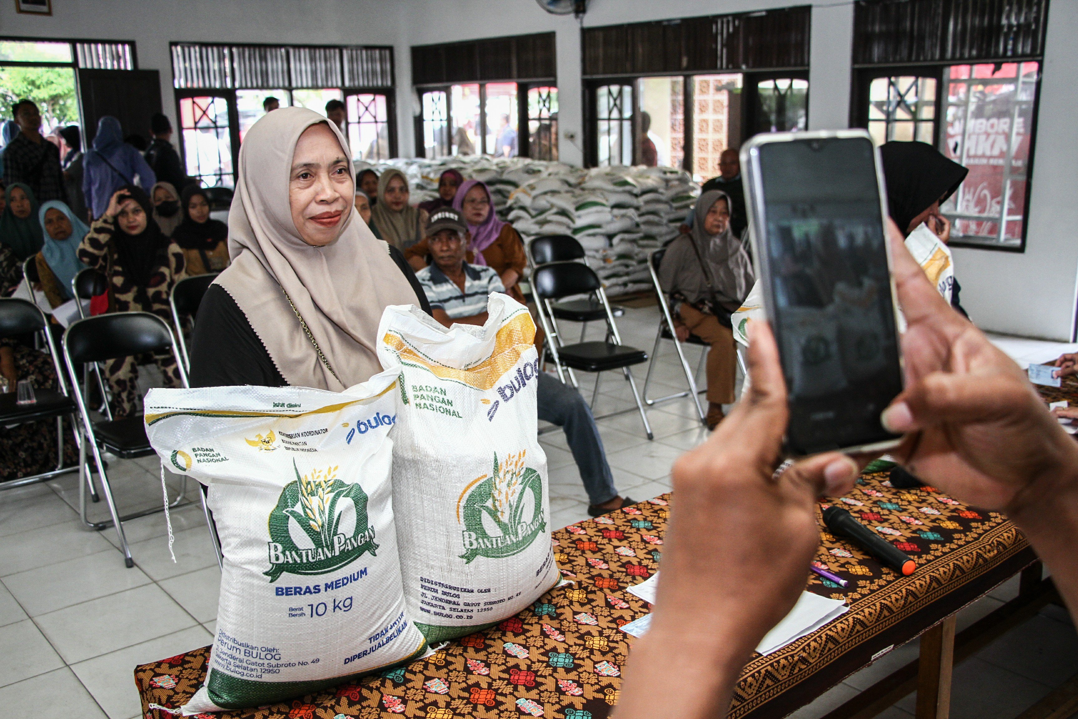 Petugas memotret bukti penerima bantuan pangan di kantor Kelurahan Panarung, Palangka Raya, Kalimantan Tengah, Senin (14/7/2025). Pemerintah Kota Palangka Raya bersinergi dengan Perum Bulog menyalurkan bantuan pangan berupa beras masing-masing 20 kilogram untuk alokasi 6.073 penerima manfaat periode Juni dan Juli 2025 dalam upaya membantu kebutuhan ekonomi masyarakat. 