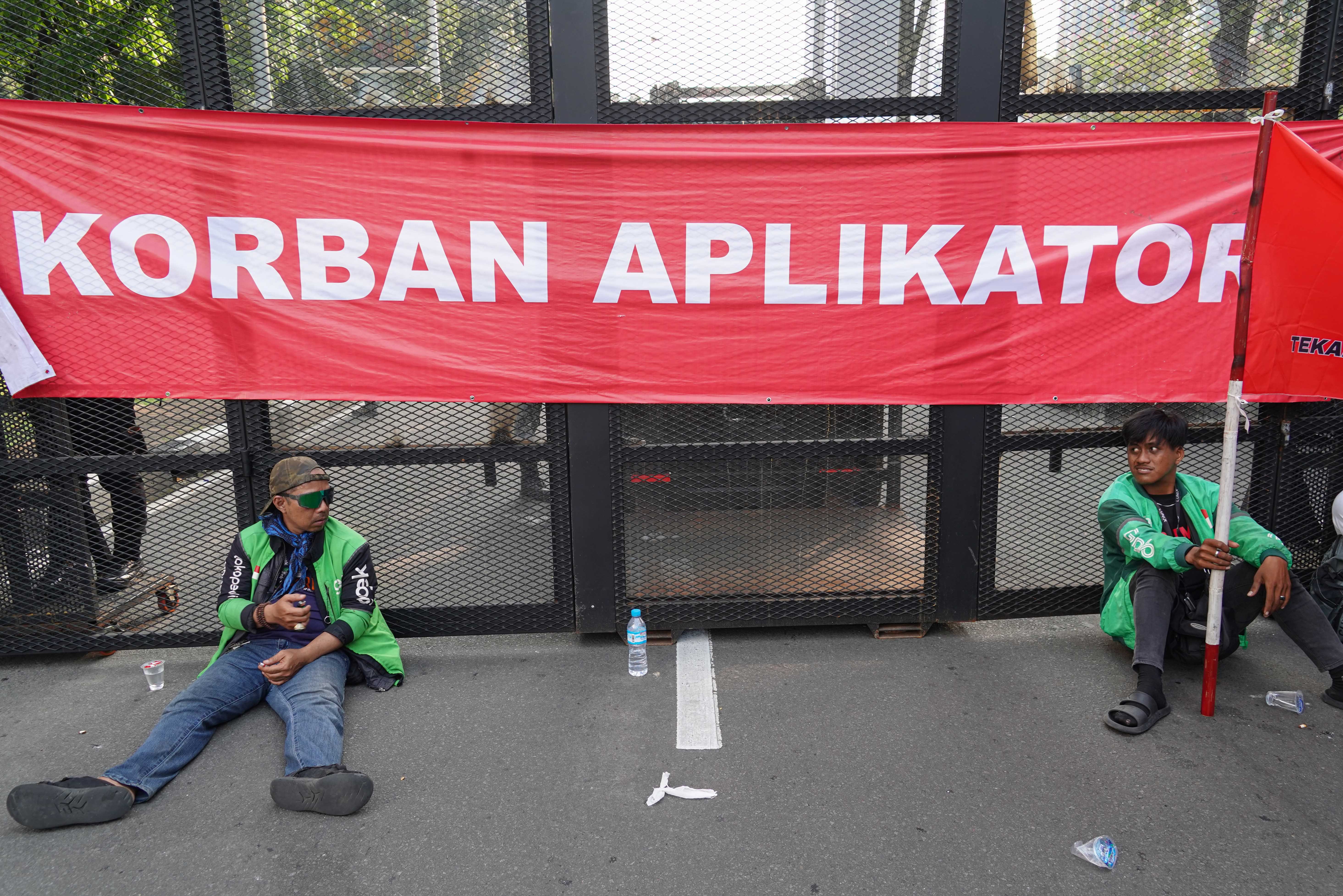 Pengemudi ojek online (ojol) yang tergabung dalam Gabungan Aksi Roda Dua (Garda) beristirahat saat melakukan demonstrasi di Jalan Merdeka Selatan, Jakarta Pusat, Senin (21/7/2025). Aksi tersebut digelar untuk mendesak pemerintah dalam membuat UU Transportasi Online dan menurunkan potongan aplikator atas layanan pengantaran orang dari 20% menjadi 10% serta menghapus program aplikator seperti hemat, aceng dan slot.