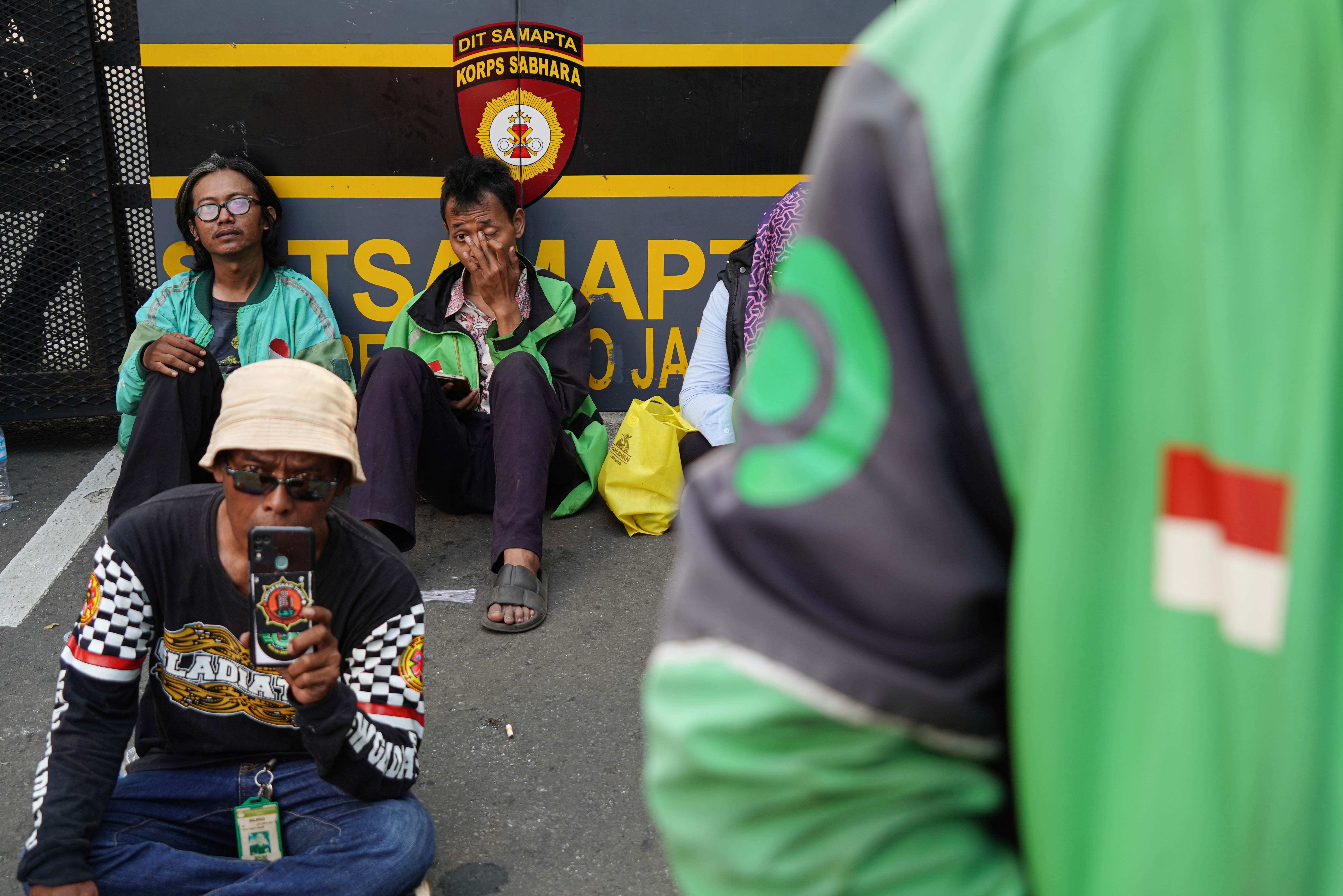 Pengemudi ojek online (ojol) yang tergabung dalam Gabungan Aksi Roda Dua (Garda) beristirahat saat melakukan demonstrasi di Jalan Merdeka Selatan, Jakarta Pusat, Senin (21/7/2025). Aksi tersebut digelar untuk mendesak pemerintah dalam membuat UU Transportasi Online dan menurunkan potongan aplikator atas layanan pengantaran orang dari 20% menjadi 10% serta menghapus program aplikator seperti hemat, aceng dan slot.