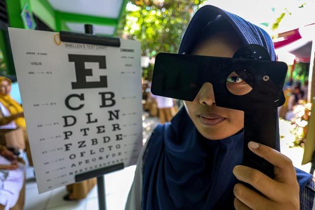 Siswi melakukan tes mata saat peluncuran program Cek Kesehatan Gratis (CKG) untuk anak sekolah di SMP Negeri 1 Padangan, Bojonegoro, Jawa Timur, Senin (4/8/2025). Program CKG Sekolah dengan target sebanyak 53,8 juta siswa dari 282 ribu satuan pendidikan mulai dari SD, SMP, SMA di seluruh Indonesia tersebut untuk mendorong deteksi dini penyakit dan meningkatkan kesadaran masyarakat terhadap pentingnya pemeriksaan kesehatan secara rutin khususnya bagi generasi muda.