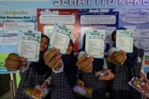 Sejumlah siswi menunjukan kartu peserta cek kesehatan saat peluncuran program Cek Kesehatan Gratis (CKG) untuk anak sekolah di SMP Negeri 1 Padangan, Bojonegoro, Jawa Timur, Senin (4/8/2025). Program CKG Sekolah dengan target sebanyak 53,8 juta siswa dari 282 ribu satuan pendidikan mulai dari SD, SMP, SMA di seluruh Indonesia tersebut untuk mendorong deteksi dini penyakit dan meningkatkan kesadaran masyarakat terhadap pentingnya pemeriksaan kesehatan secara rutin khususnya bagi generasi muda.