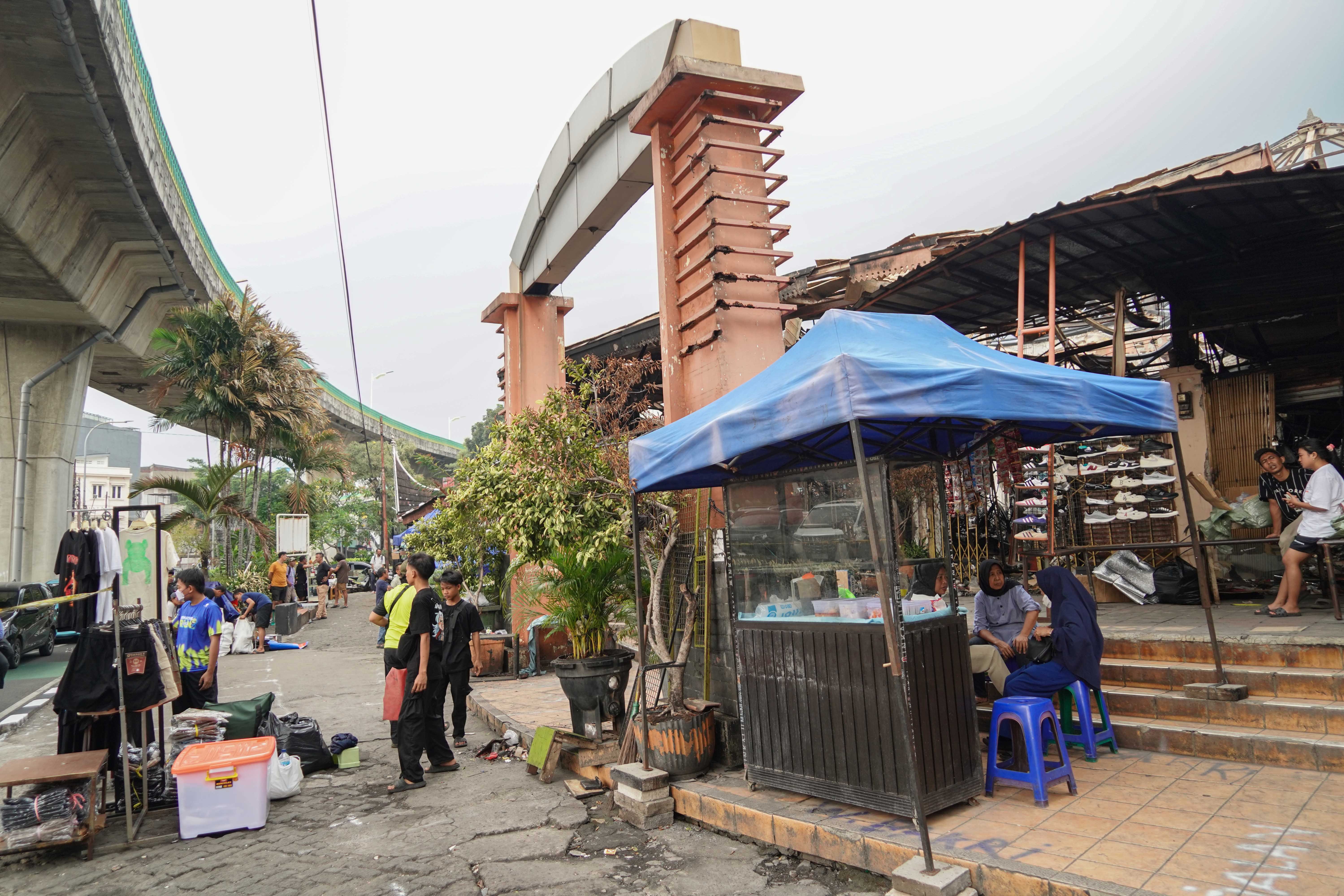 Suasana pedagang di Pasar Taman Puring, Kebayoran Baru, Jakarta Selatan, Senin (4/8/2025). Sepekan pascakebakaran yang menghanguskan 552 kios pada Senin (28/7/2025) malam, sejumlah pedagang memanfaatkan trotoar di depan pasar untuk menjajakan barang dagangannya sambil menanti kejelasan pasar tersebut dibangun kembali.