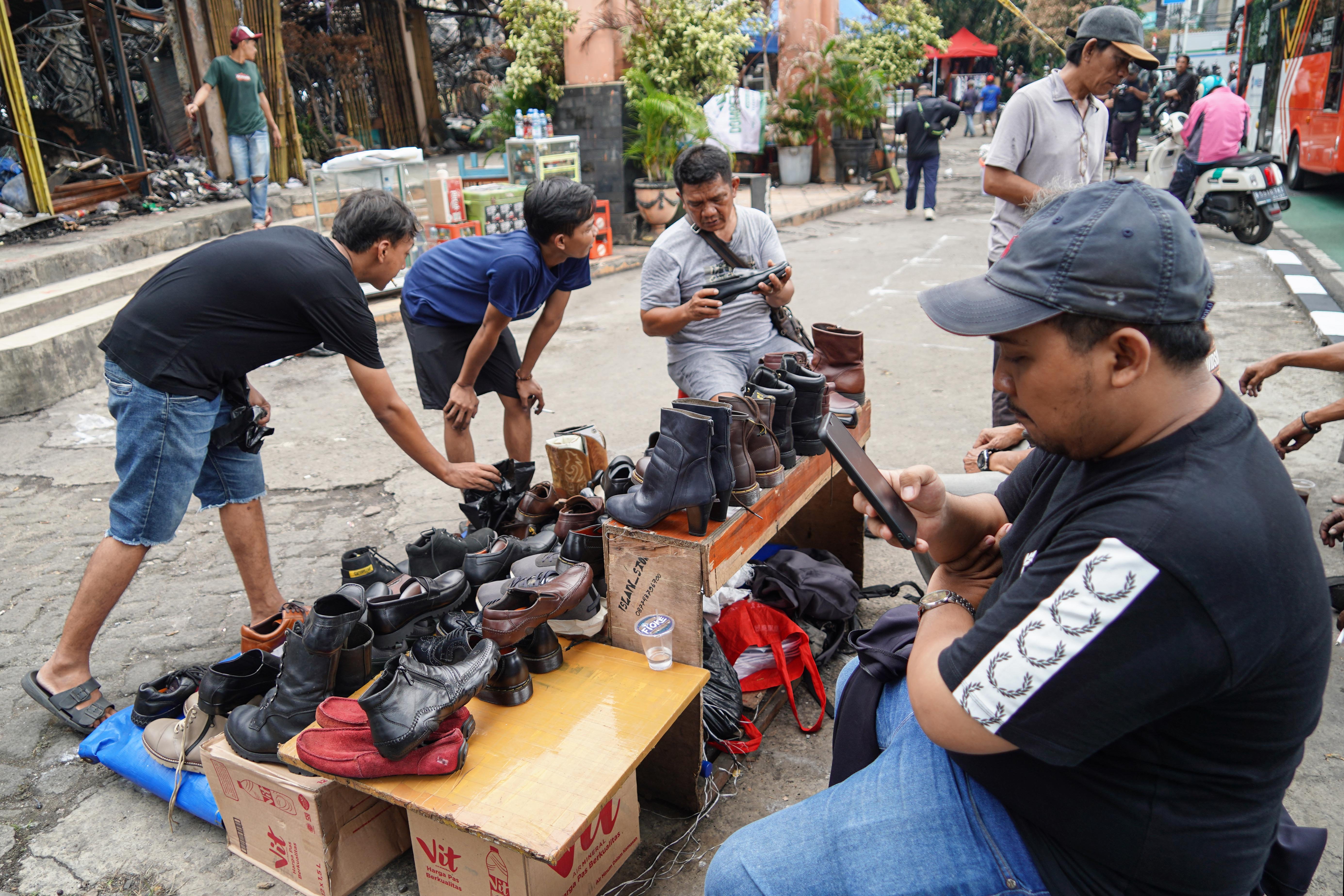 Pedagang melayani pembeli di Pasar Taman Puring, Kebayoran Baru, Jakarta Selatan, Senin (4/8/2025). Sepekan pascakebakaran yang menghanguskan 552 kios pada Senin (28/7/2025) malam, sejumlah pedagang memanfaatkan trotoar di depan pasar untuk menjajakan barang dagangannya sambil menanti kejelasan pasar tersebut dibangun kembali.