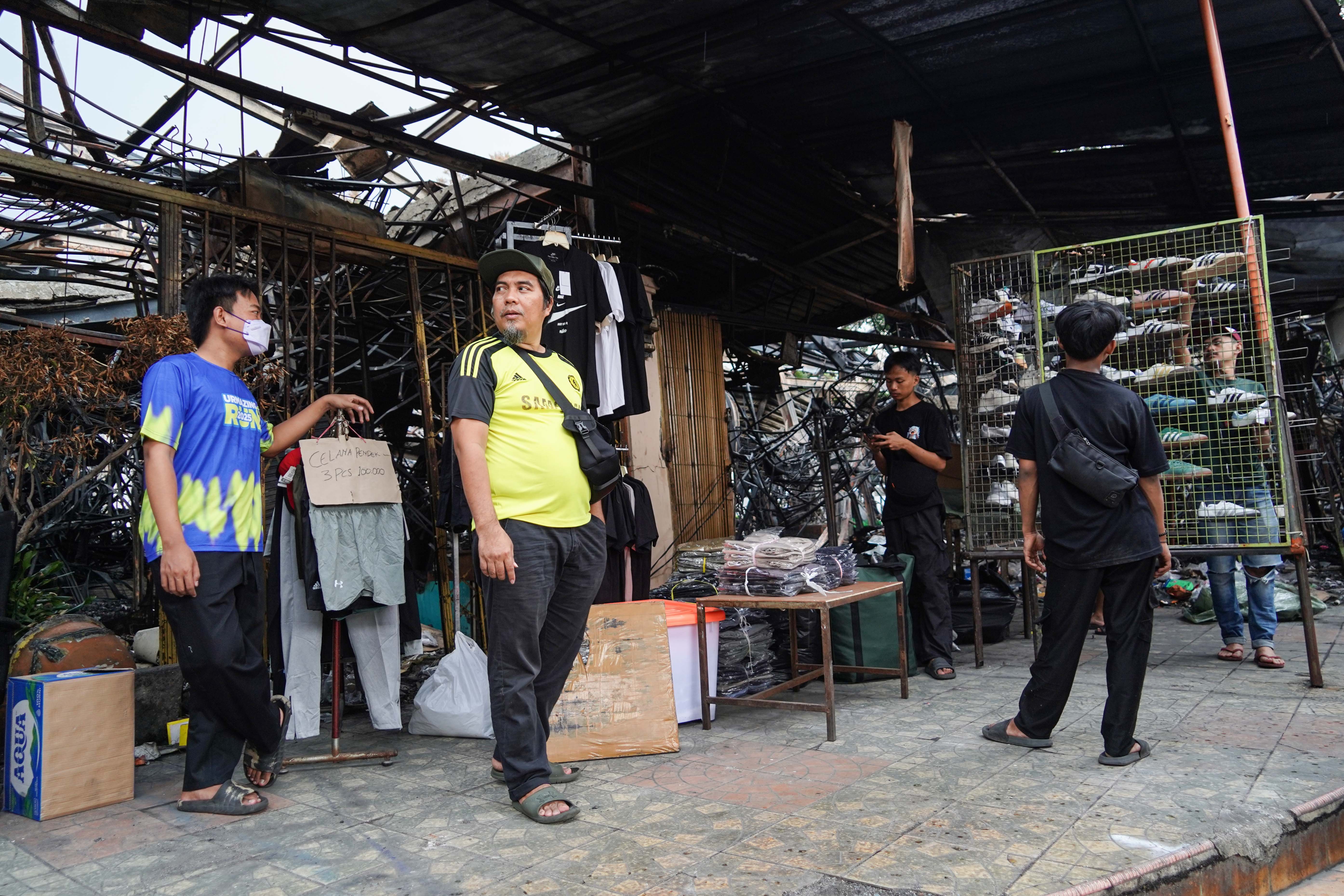 Pedagang menunggu pembeli di Pasar Taman Puring, Kebayoran Baru, Jakarta Selatan, Senin (4/8/2025). Sepekan pascakebakaran yang menghanguskan 552 kios pada Senin (28/7/2025) malam, sejumlah pedagang memanfaatkan trotoar di depan pasar untuk menjajakan barang dagangannya sambil menanti kejelasan pasar tersebut dibangun kembali.