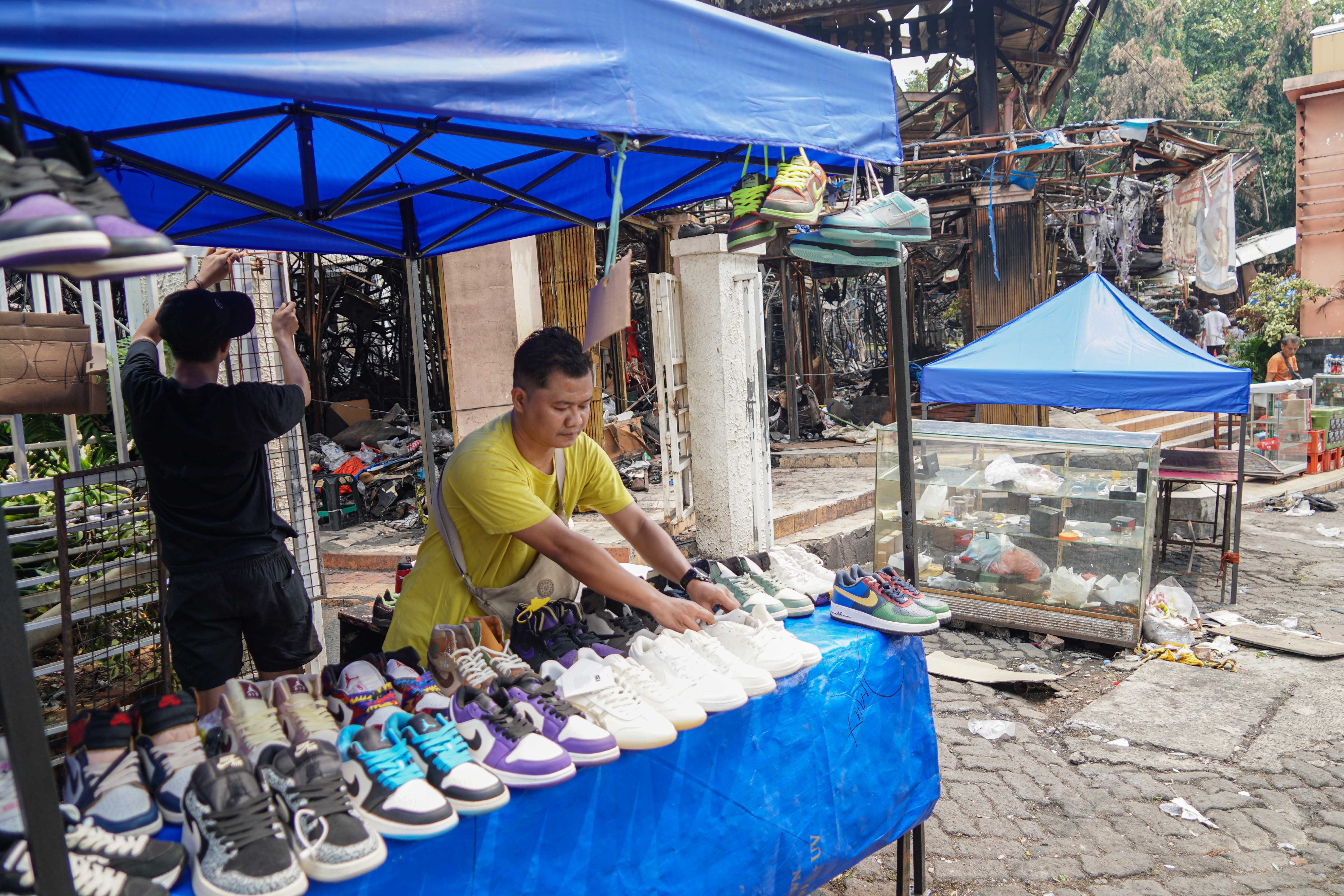 Pedagang menata sepatu yang dijual di Pasar Taman Puring, Kebayoran Baru, Jakarta Selatan, Senin (4/8/2025). Sepekan pascakebakaran yang menghanguskan 552 kios pada Senin (28/7/2025) malam, sejumlah pedagang memanfaatkan trotoar di depan pasar untuk menjajakan barang dagangannya sambil menanti kejelasan pasar tersebut dibangun kembali.