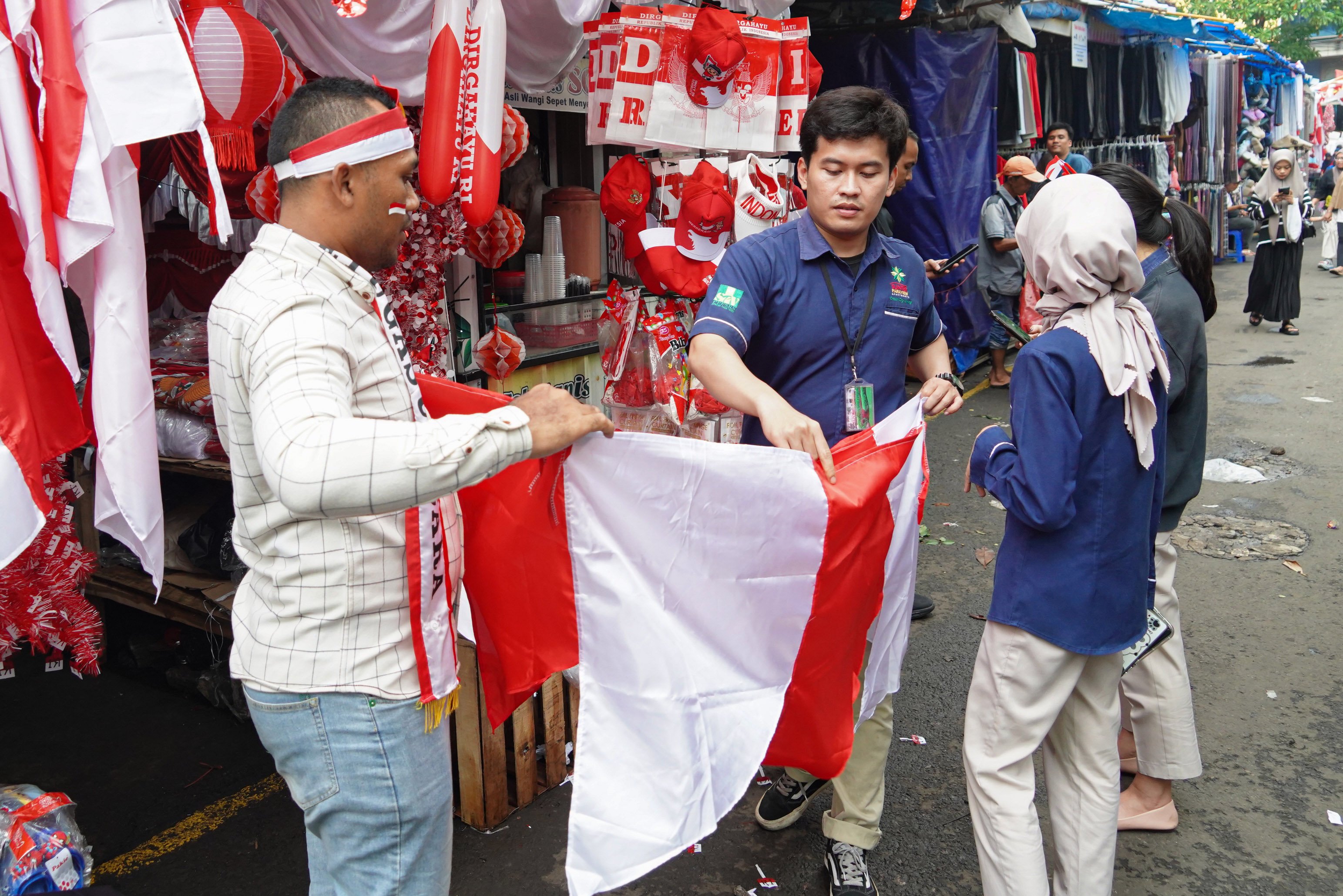 Warga melihat bendera merah putih yang dijual di Pasar Jatinegara, Jakarta Timur, Senin (11/8/2025). Hiasan bertemakan HUT ke-80 Kemerdekaan Republik Indonesia seperti stiker, balon, bendera dan umbul-umbul tersebut dijual dengan harga kisaran mulai dari Rp2.000 hingga jutaan rupiah tergantung jenis dan ukurannya.