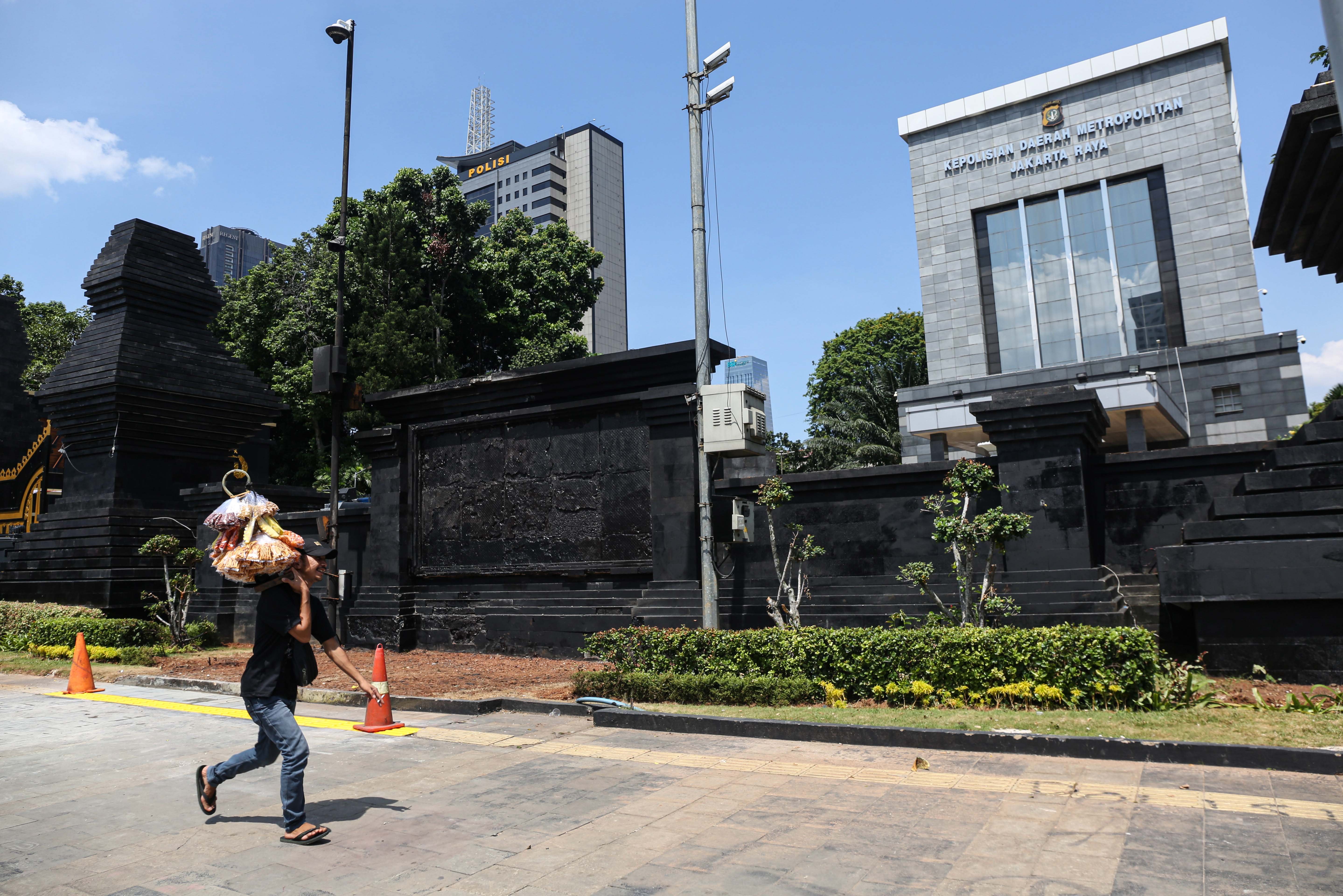 Pedagang asongan berjalan di trotoar depan Polda Metro Jaya, Jalan Jenderal Sudirman, Jakarta, Selasa (2/9/2025). Situasi di sekitar kawasan tersebut kembali kondusif setelah sebelumnya pada Jumat (29/8) terjadi aksi unjuk rasa yang berujung kericuhan.