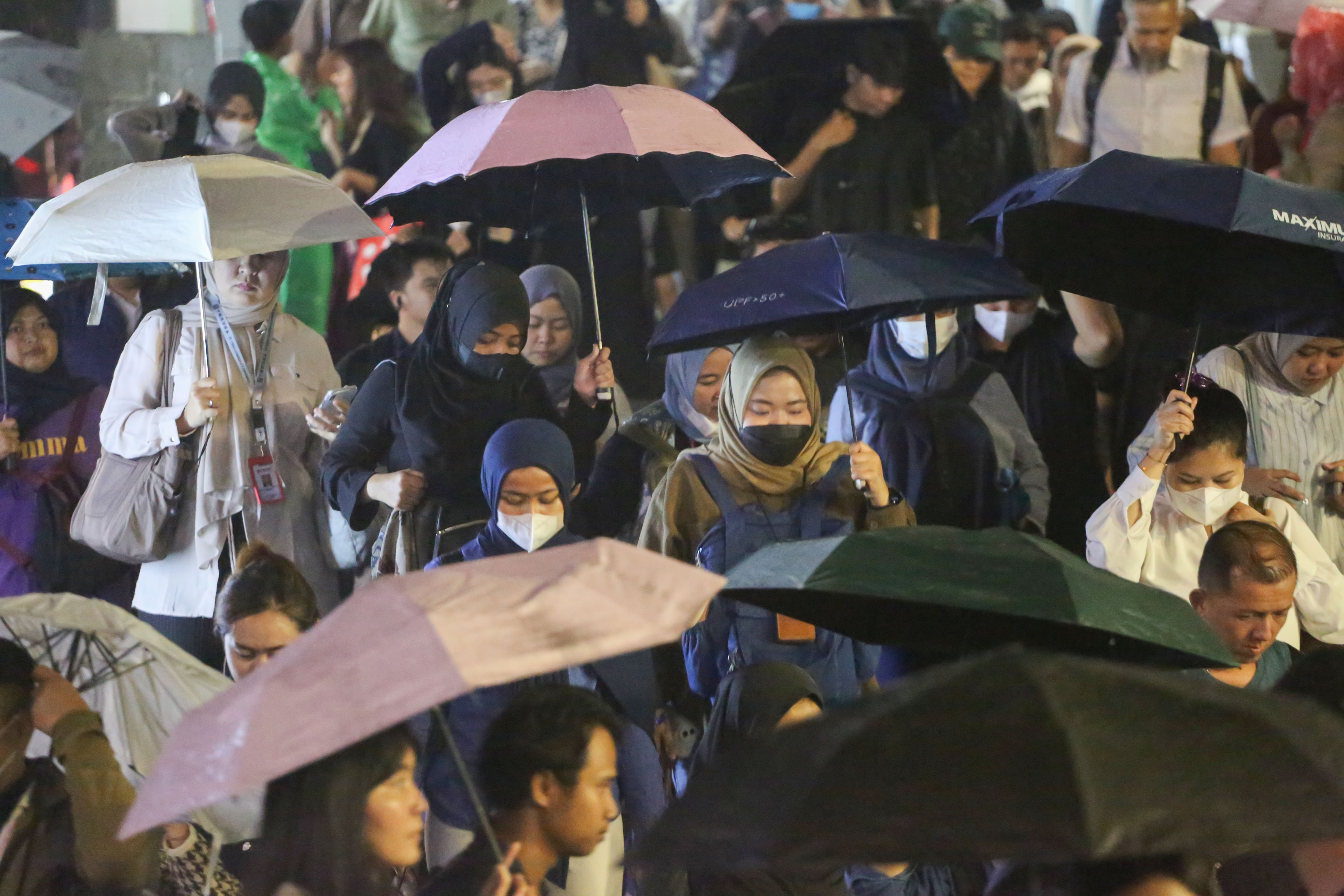 Warga memakai payung saat hujan di kawasan Dukuh Atas, Jakarta, Rabu (29/10/2025). Menteri Kesehatan, Budi Gunadi Sadikin menghimbau kepada masyarakat untuk mengenakan masker dan mengurangi aktivitas setelah hujan menyusul temuan Badan Riset dan Inovasi Nasional (BRIN) yang mengungkap air hujan di Jakarta mengandung mikroplastik.