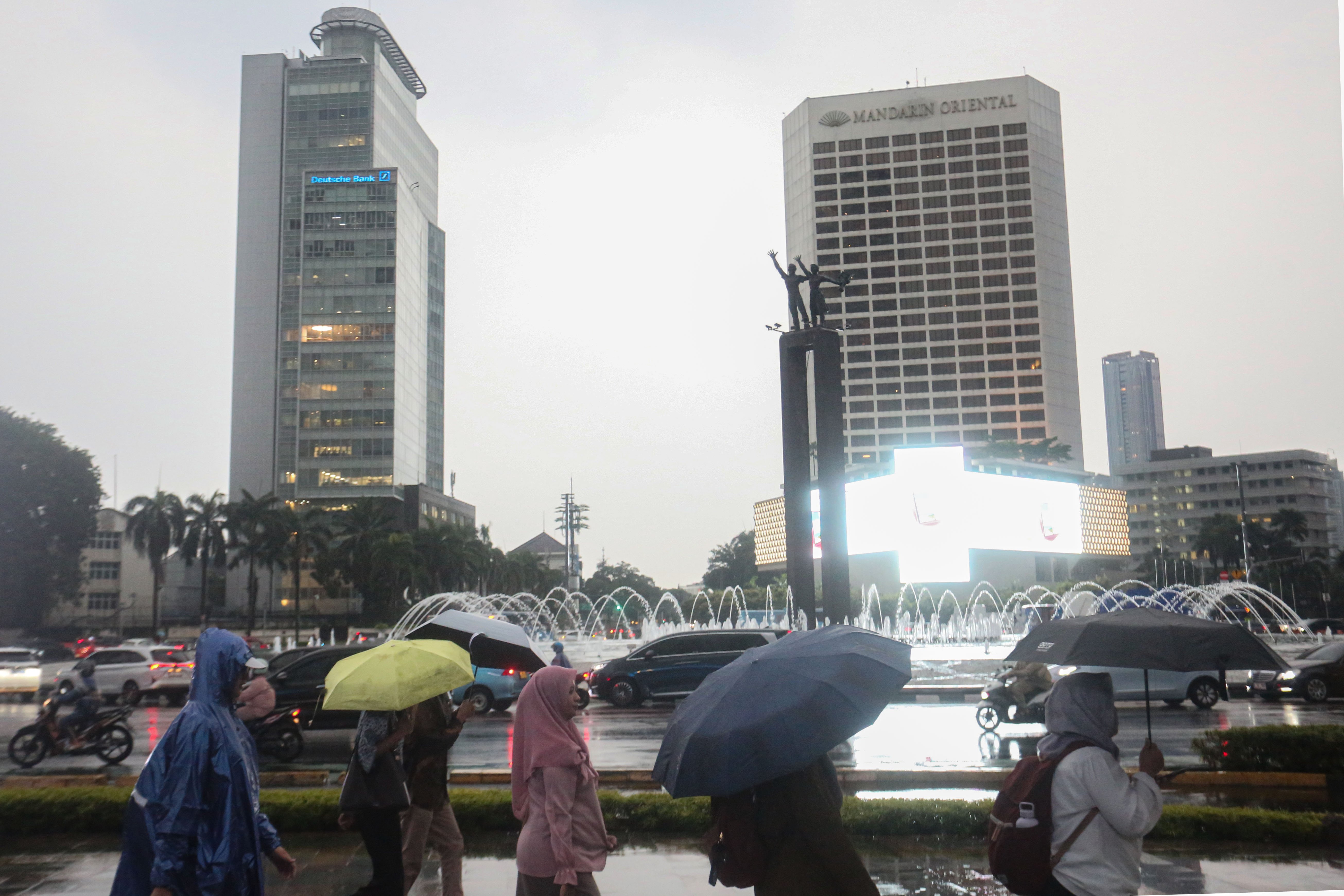 Warga memakai payung saat hujan di kawasan Bundaran HI, Jakarta, Rabu (29/10/2025). Menteri Kesehatan, Budi Gunadi Sadikin menghimbau kepada masyarakat untuk mengenakan masker dan mengurangi aktivitas setelah hujan menyusul temuan Badan Riset dan Inovasi Nasional (BRIN) yang mengungkap air hujan di Jakarta mengandung mikroplastik.