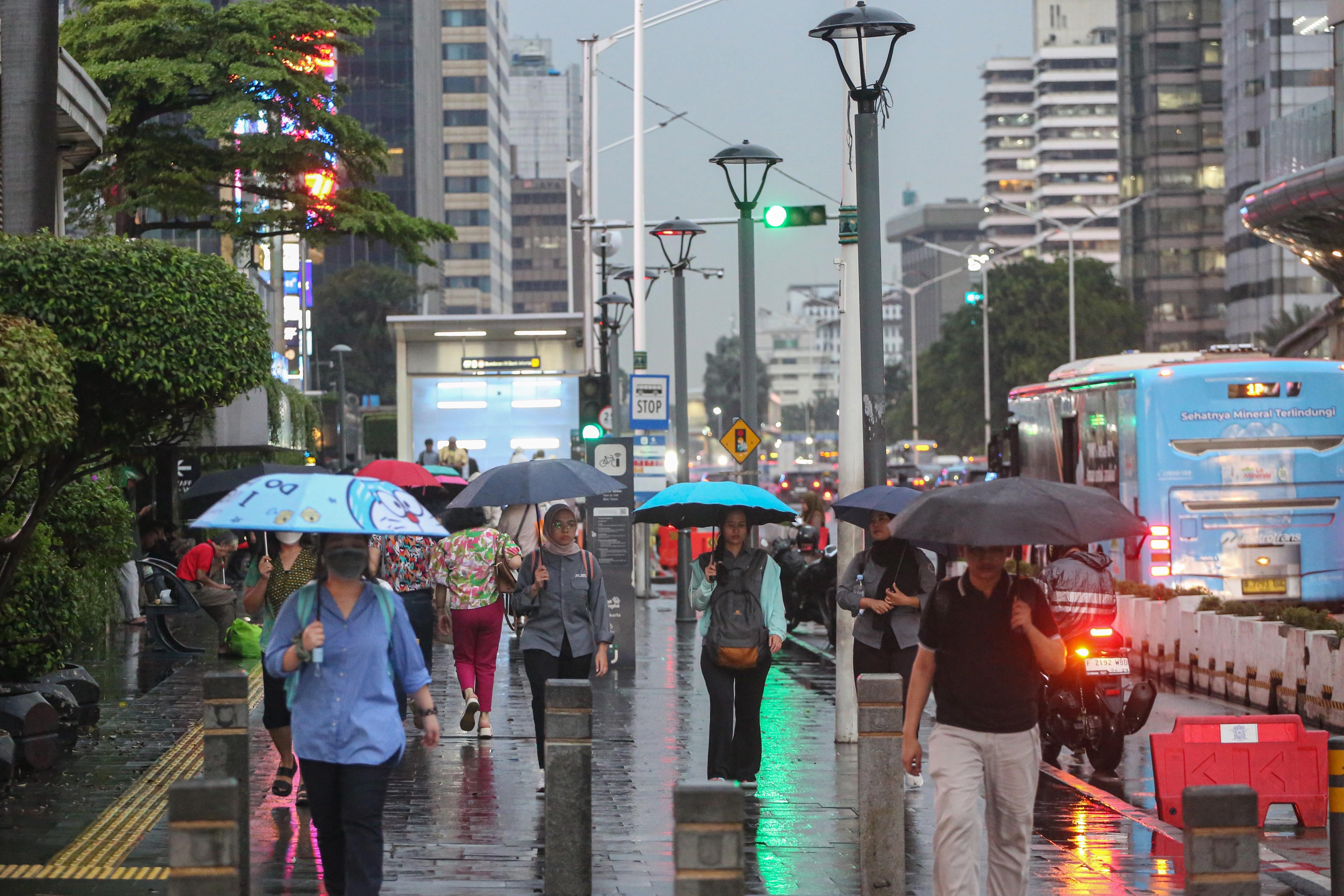 Warga memakai payung saat hujan di kawasan Bundaran HI, Jakarta, Rabu (29/10/2025). Menteri Kesehatan, Budi Gunadi Sadikin menghimbau kepada masyarakat untuk mengenakan masker dan mengurangi aktivitas setelah hujan menyusul temuan Badan Riset dan Inovasi Nasional (BRIN) yang mengungkap air hujan di Jakarta mengandung mikroplastik.