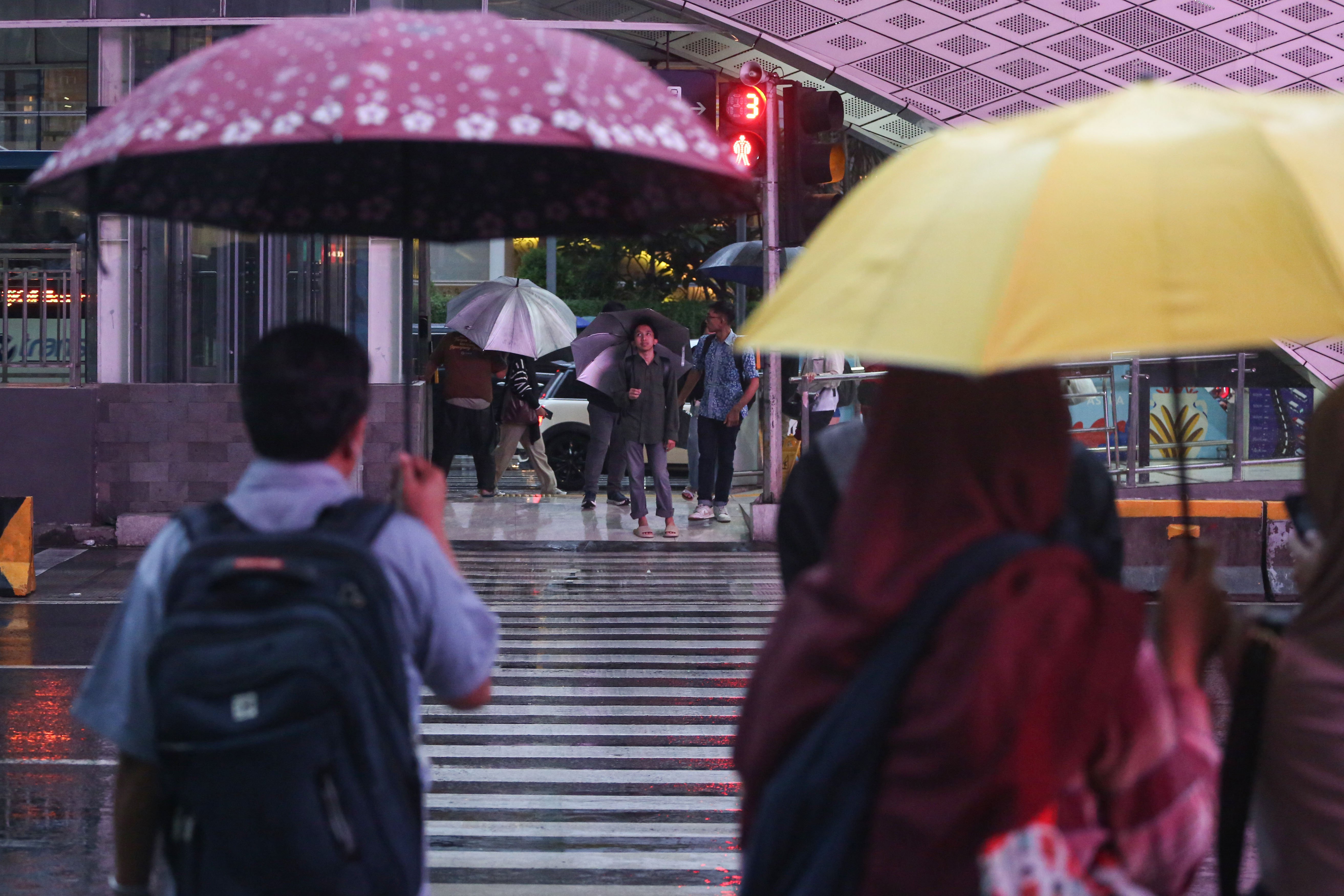 Warga memakai payung saat hujan di kawasan Bundaran HI, Jakarta, Rabu (29/10/2025). Menteri Kesehatan, Budi Gunadi Sadikin menghimbau kepada masyarakat untuk mengenakan masker dan mengurangi aktivitas setelah hujan menyusul temuan Badan Riset dan Inovasi Nasional (BRIN) yang mengungkap air hujan di Jakarta mengandung mikroplastik.