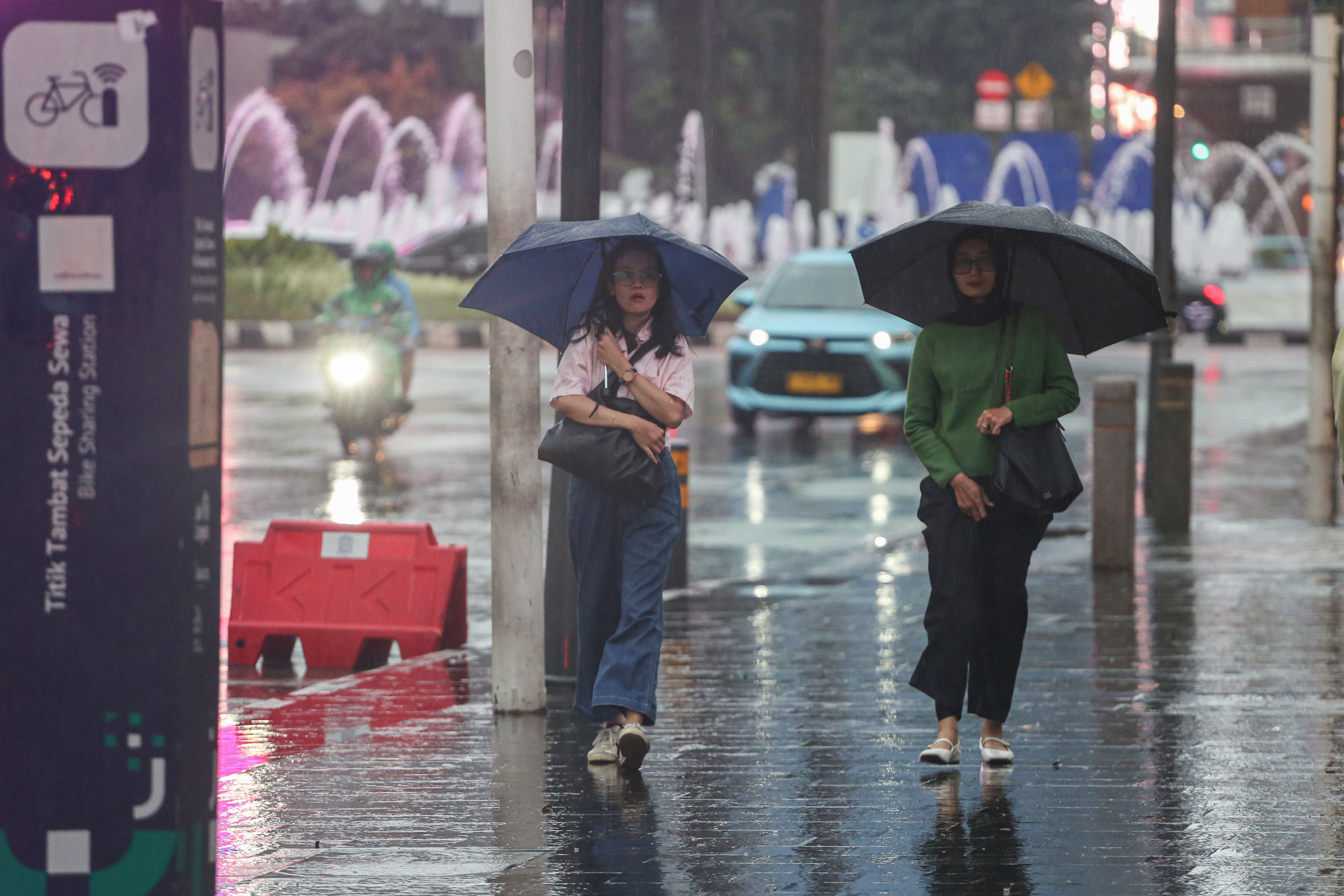 Warga memakai payung saat hujan di kawasan Bundaran HI, Jakarta, Rabu (29/10/2025). Menteri Kesehatan, Budi Gunadi Sadikin menghimbau kepada masyarakat untuk mengenakan masker dan mengurangi aktivitas setelah hujan menyusul temuan Badan Riset dan Inovasi Nasional (BRIN) yang mengungkap air hujan di Jakarta mengandung mikroplastik.