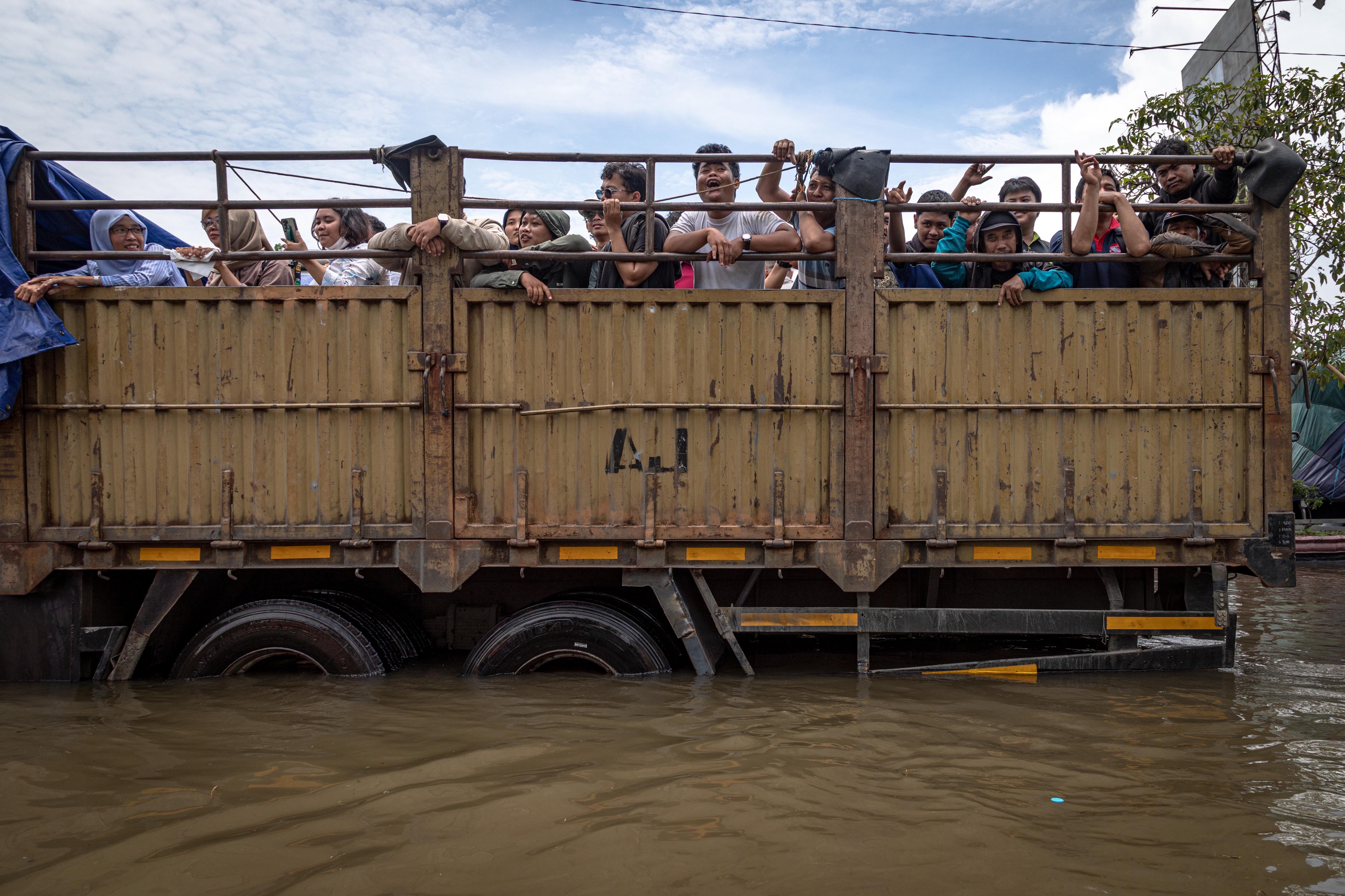 Warga menumpang truk untuk menembus banjir yang menggenangi jalur utama pantura Semarang-Surabaya, Jalan Kaligawe Raya, Semarang, Jawa Tengah, Kamis (23/10/2025). Banjir di wilayah tersebut mengalami peningkatan dari sekitar 40 sentimeter pada Rabu (22/10) menjadi sekitar 75 sentimeter pada Kamis (23/10), sehingga menyebabkan lalu lintas tersendat hingga sekitar enam kilometer. 
