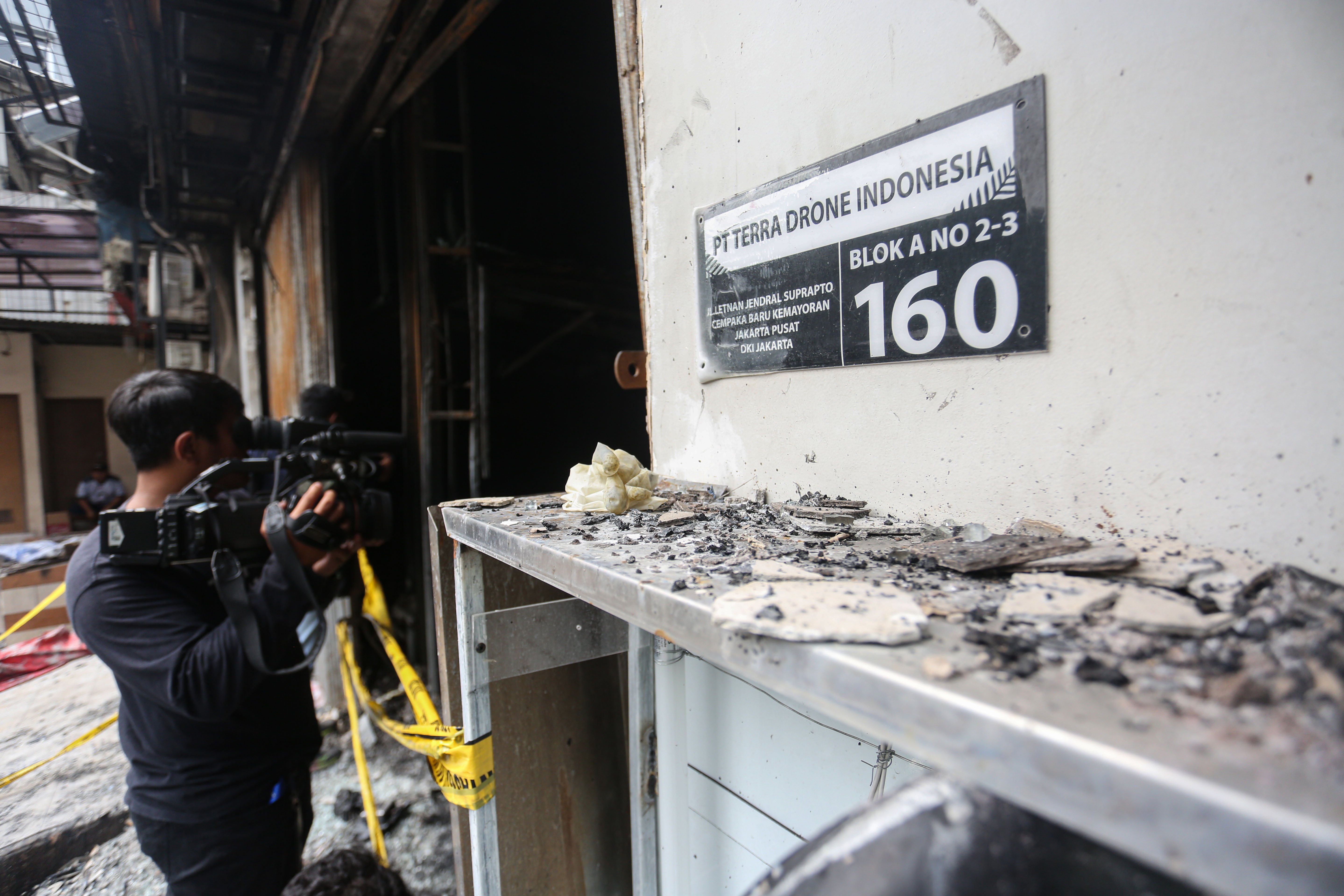 Wartawan mengambil gambar suasana lantai dasar ruko PT Terra Drone Indonesia usai terbakar di Jalan Letnan Jenderal Suprapto, Cempaka Baru, Kemayoran, Jakarta Pusat, Rabu (10/12/2025). Kebakaran yang menghanguskan roku tujuh lantai yang terjadi pada Selasa (9/12) itu menewaskan 22 orang dengan 15 diantaranya perempuan dan tujuh orang lainnya laki-laki.