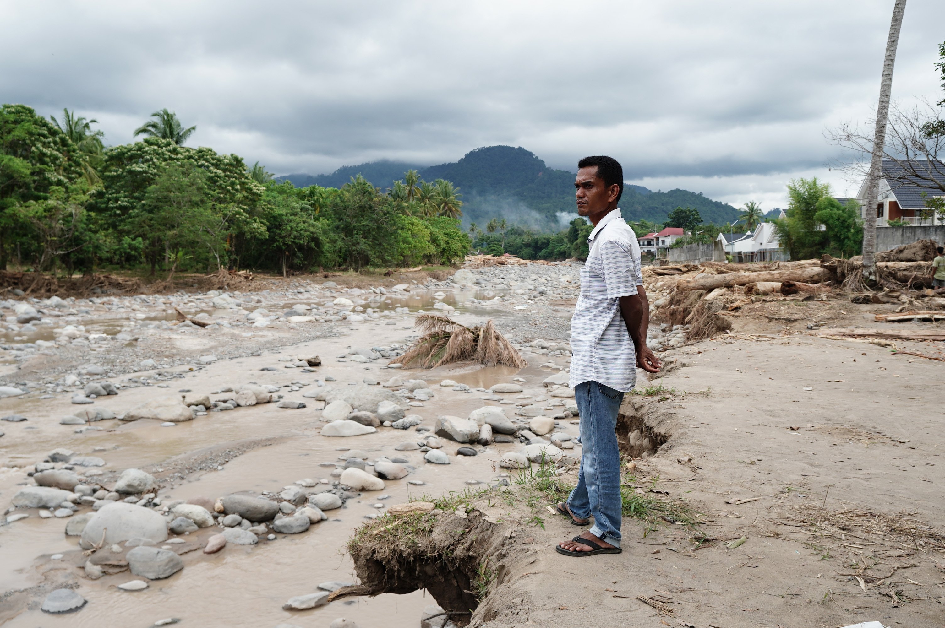 Seorang warga memperhatikan sungai setelah terjadinya banjir bandang di Kampung Apa, Kecamatan Koto Tangah, Padang, Sumatera Barat, Jumat (5/12/2025). Derasnya aliran air dengan material gelondongan kayu dan batu besar yang ikut terbawa hingga menyebabkan bendungan jebol saat banjir bandang melanda kawasan tersebut pada Kamis (27/11) mengakibatkan delapan orang meninggal dunia dan 18 rumah hilang tersapu air.