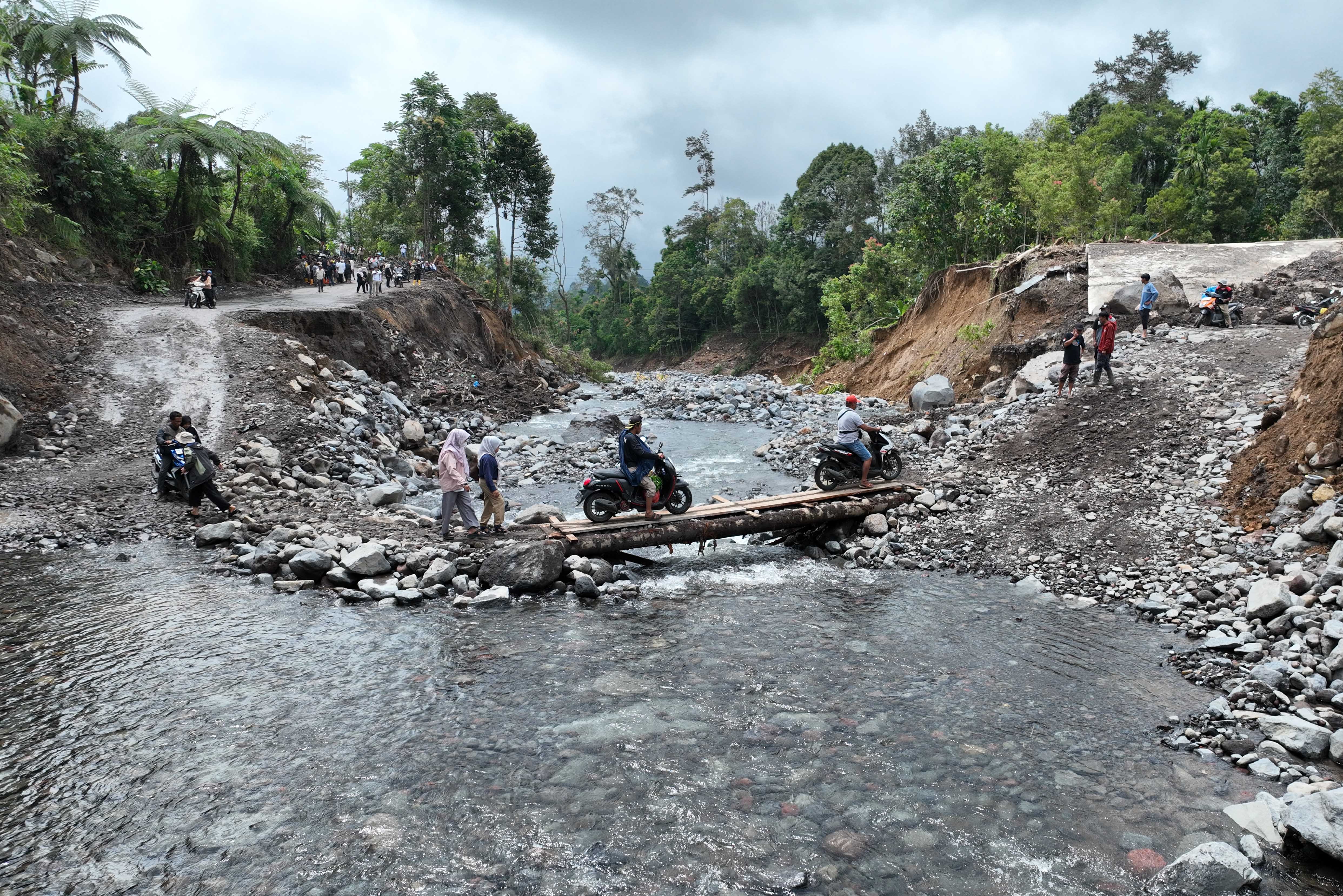 Warga melintasi sungai dengan jembatan darurat yang dibuat usai jembatan permanen diterjang banjir bandang di Kecamatan Malalak, Kabupaten Agam, Sumatera Barat, Minggu (7/12/2025). Sebanyak tiga dusun atau jorong di wilayah tersebut masih terisolir karena terputusnya akses jalan sehingga membuat distribusi logistik terhambat.