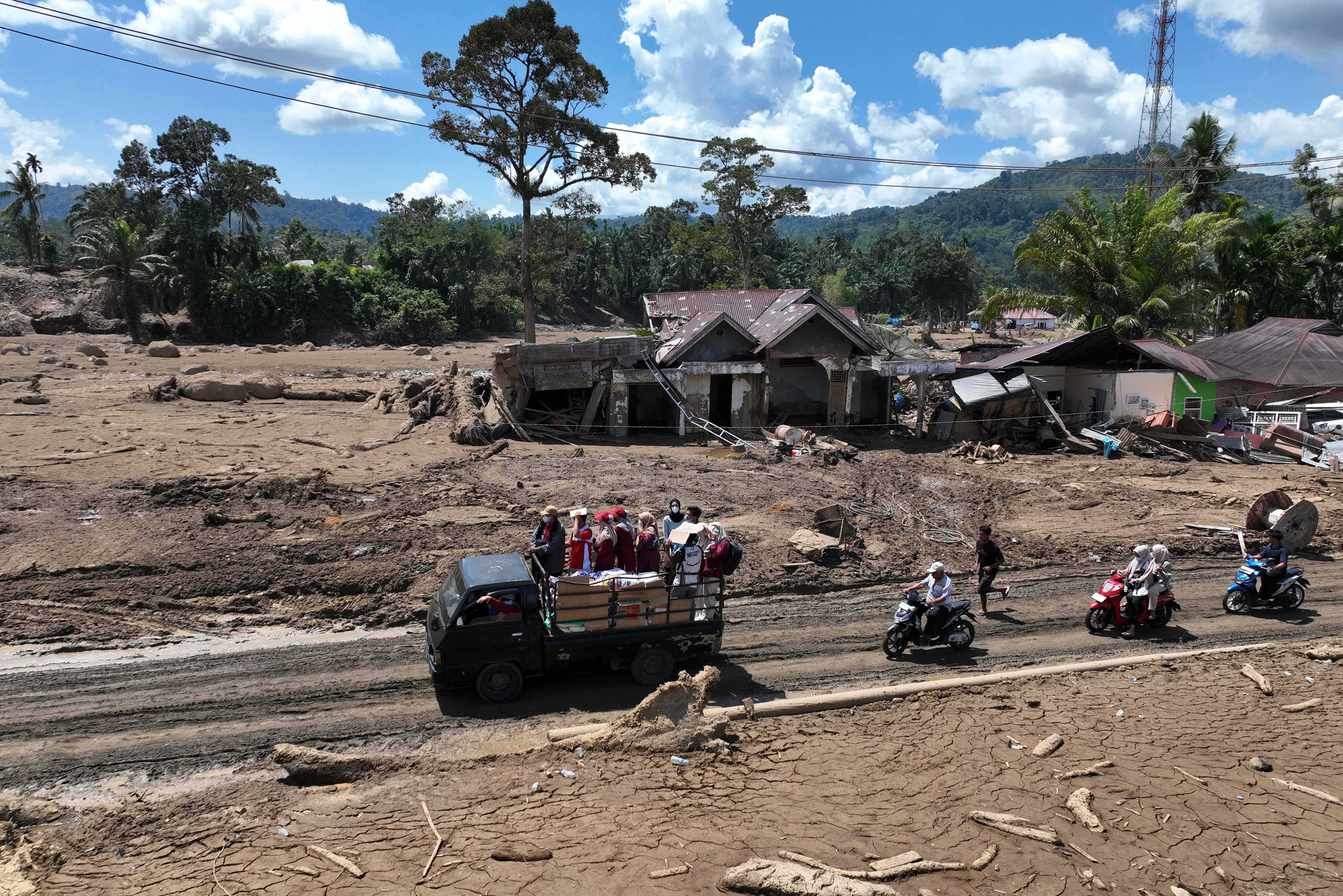 Foto udara sejumlah kendaraan melintas di dekat rumah warga yang rusak setelah terjadinya banjir bandang di Salareh Aia, Palembayan, Sumatera Barat, Sabtu (6/12/2025). Banjir bandang yang menerjang kawasan itu pada Kamis (27/11) menyebabkan rumah warga rusak dan 122 orang meninggal dunia. 