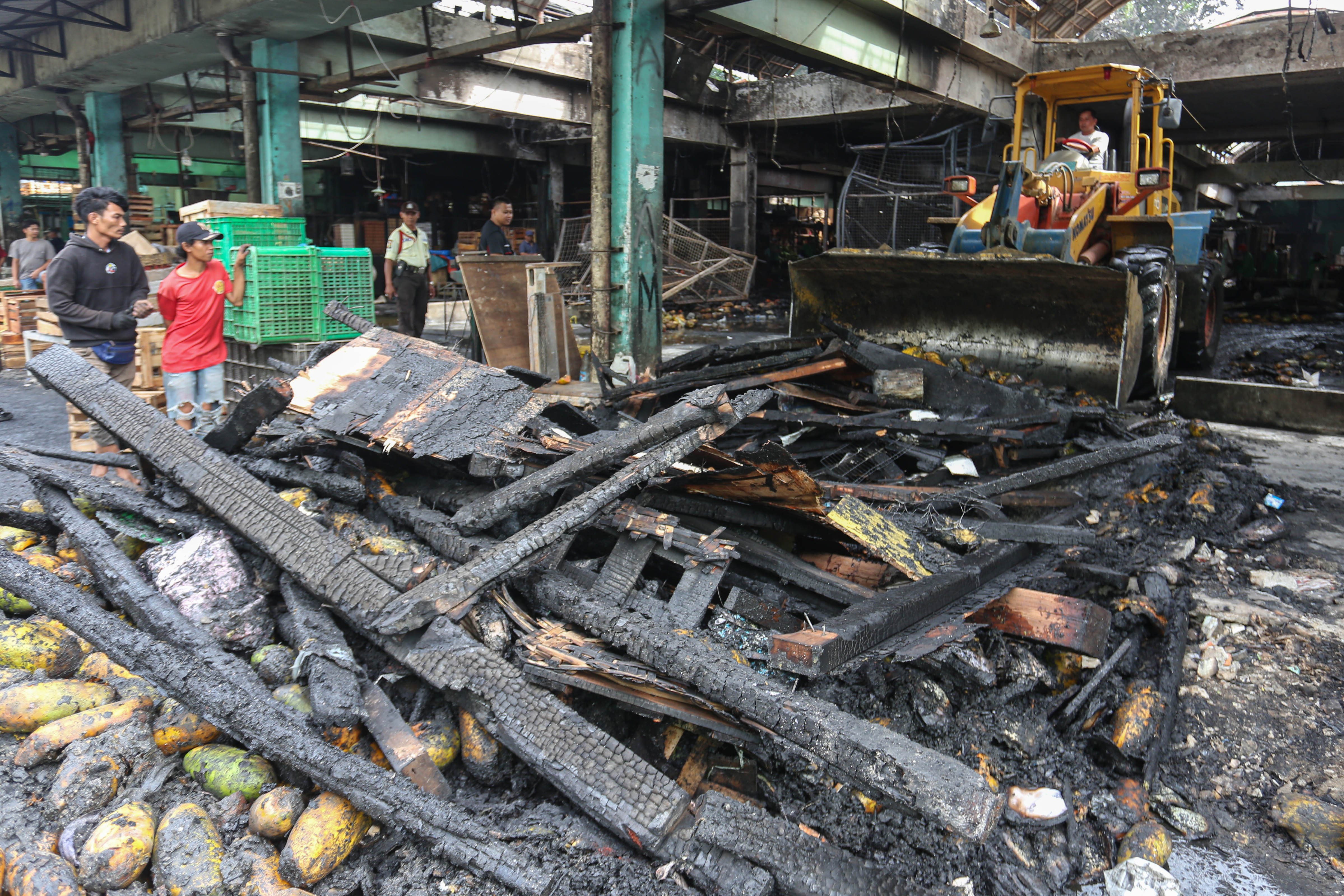 Petugas membersihkan puing-puing kebakaran kios pedagang di Pasar Induk Kramat Jati, Jakarta Timur, Senin (15/12/2025). Kebakaran yang diduga akibat korsleting listrik tersebut menyebabkan 350 kios pedagang hangus terbakar dengan kerugian mencapai Rp10 miliar.