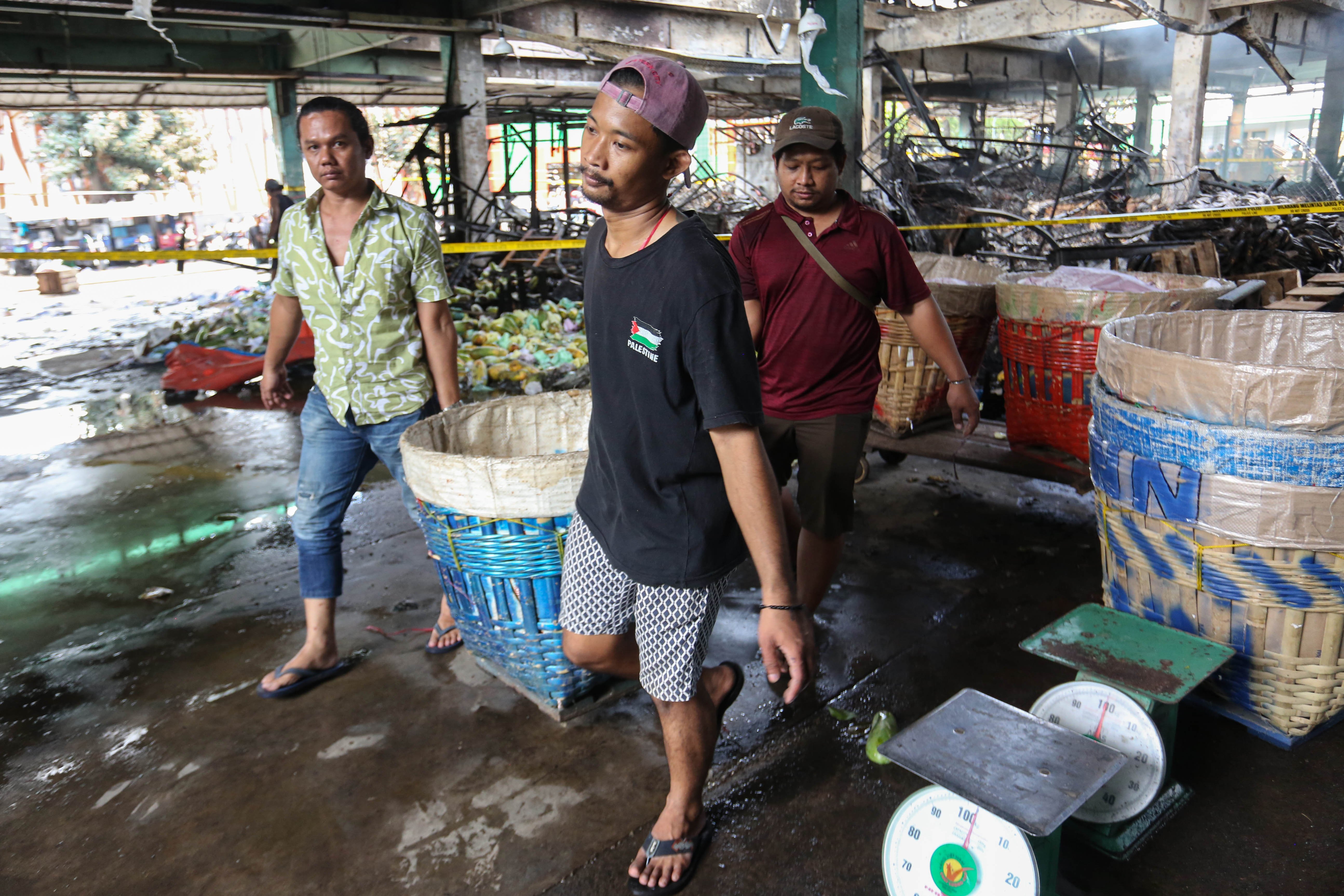 Pedagang mengangkut buah pepaya usai kios tempat berjualannya terbakar di Pasar Induk Kramat Jati, Jakarta Timur, Senin (15/12/2025). Kebakaran yang diduga akibat korsleting listrik tersebut menyebabkan 350 kios pedagang hangus terbakar dengan kerugian mencapai Rp10 miliar.
