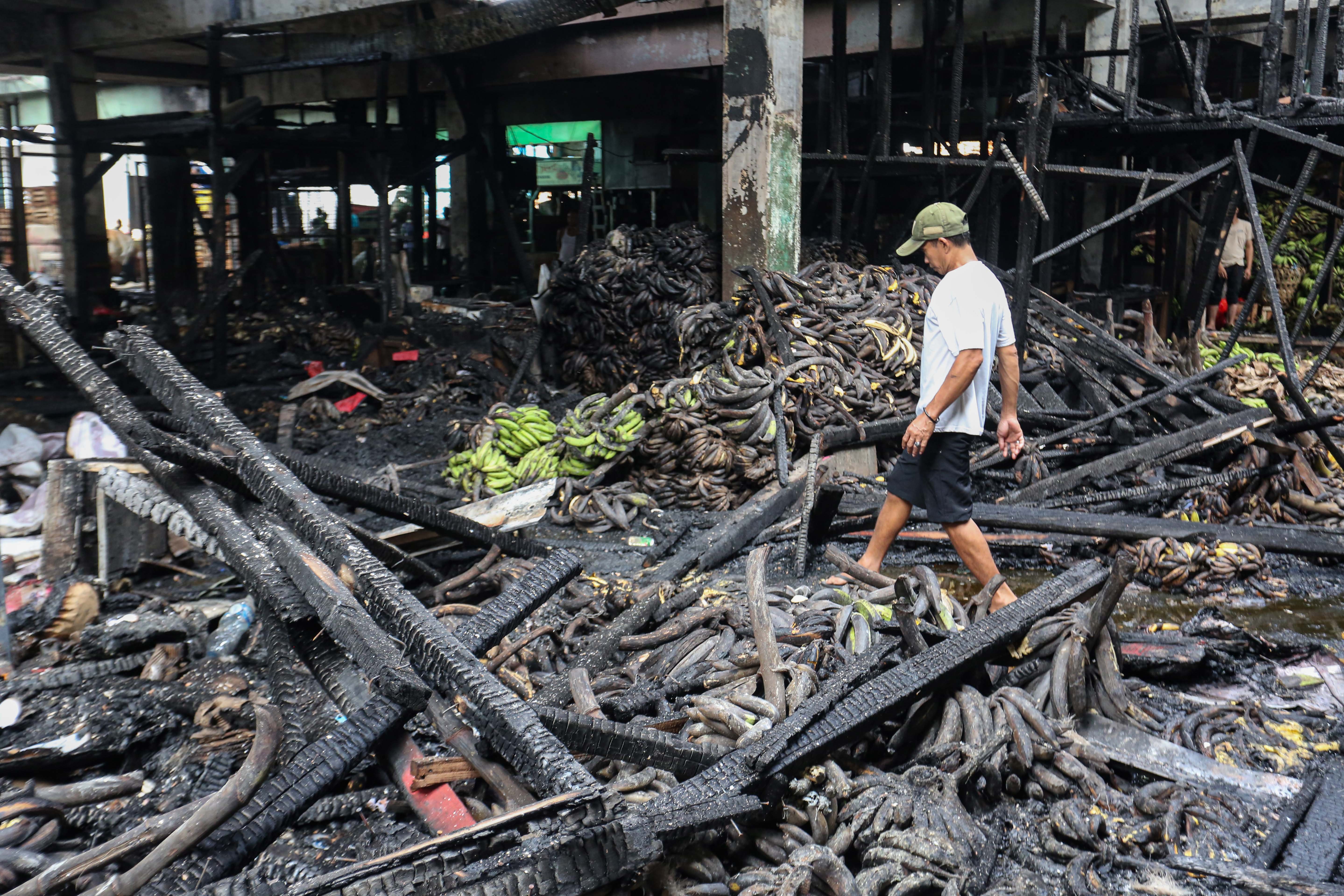 Pedagang berjalan di puing-puing kios tempat berjualannya usai terbakar di Pasar Induk Kramat Jati, Jakarta Timur, Senin (15/12/2025). Kebakaran yang diduga akibat korsleting listrik tersebut menyebabkan 350 kios pedagang hangus terbakar dengan kerugian mencapai Rp10 miliar.