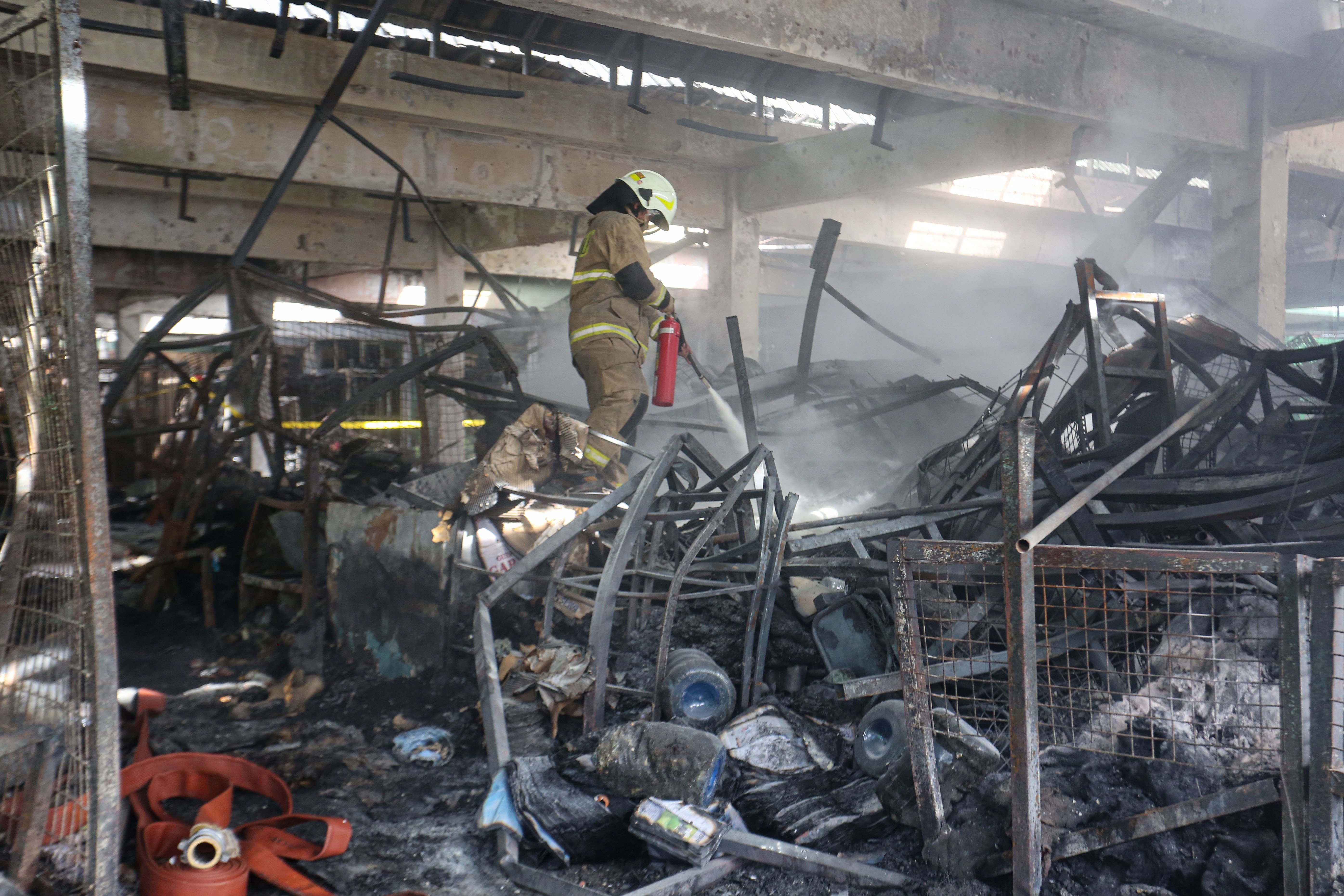 Petugas pemadam kebakaran melakukan pendinginan api yang membakar kios pedagang di Pasar Induk Kramat Jati, Jakarta Timur, Senin (15/12/2025). Kebakaran yang diduga akibat korsleting listrik tersebut menyebabkan 350 kios pedagang hangus terbakar dengan kerugian mencapai Rp10 miliar.