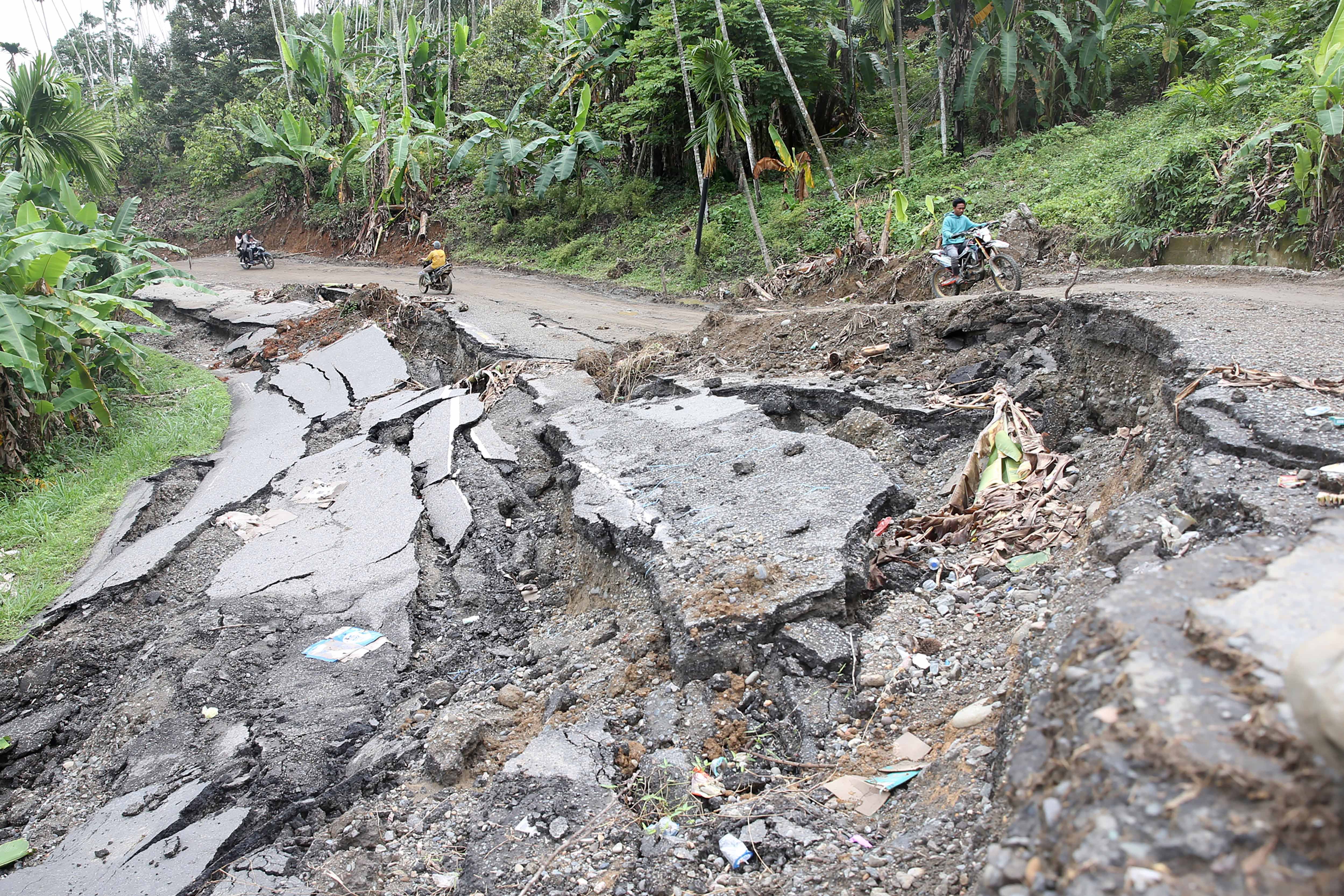 Pengendara sepeda motor melintasi jalan negara Bireuen-Takengon yang amblas di Bireuen, Aceh, Senin (15/12/2025). Bencana alam akibat hujan deras akhir November lalu mengakibatkan sekitar 17 titik longsor yang menutupi badan jalan dan 18 lokasi badan jalan amblas dari Juli Bireuen hingga kilometer 45 Bener Meriah. 