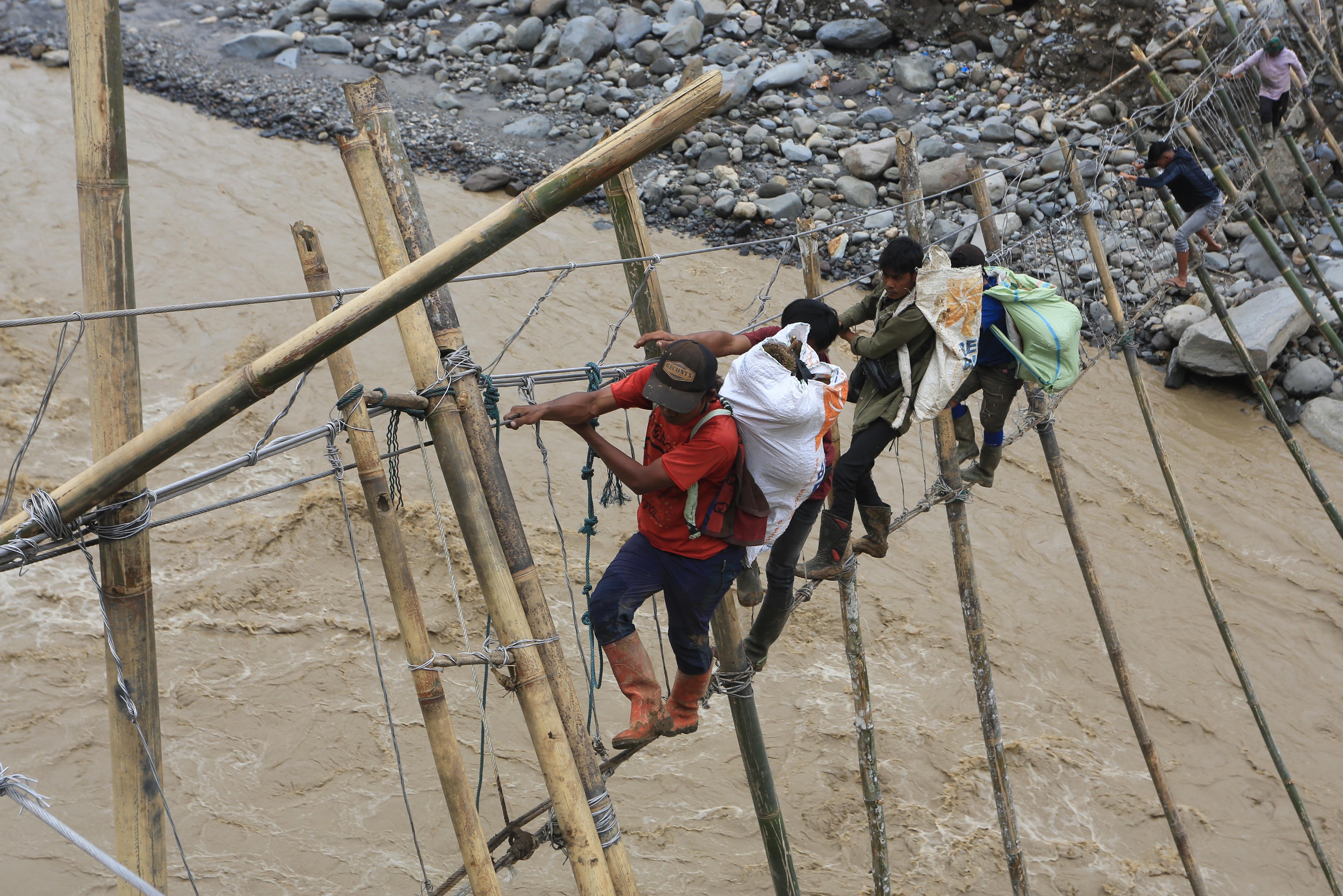 Warga melintasi sungai lewat jembatan tali darurat penghubung dari Desa Bergang Kecamatan Ketol, Aceh Tengah dan Desa Simpang Rahmat, Gajah Putih, Bener Meriah, Aceh, Minggu (14/12/2025). Berdasarkan data pos Komando tanggap darurat bencana Aceh sebanyak 1.464 jiwa dari Desa Bergang, Karang Ampar dan Desa Pantan Reduk kecamatan Ketol masih terisolir akibat akses jalan dan jembatan putus pasca bencana hidrometeorologi pada Rabu (26/11) lalu. 