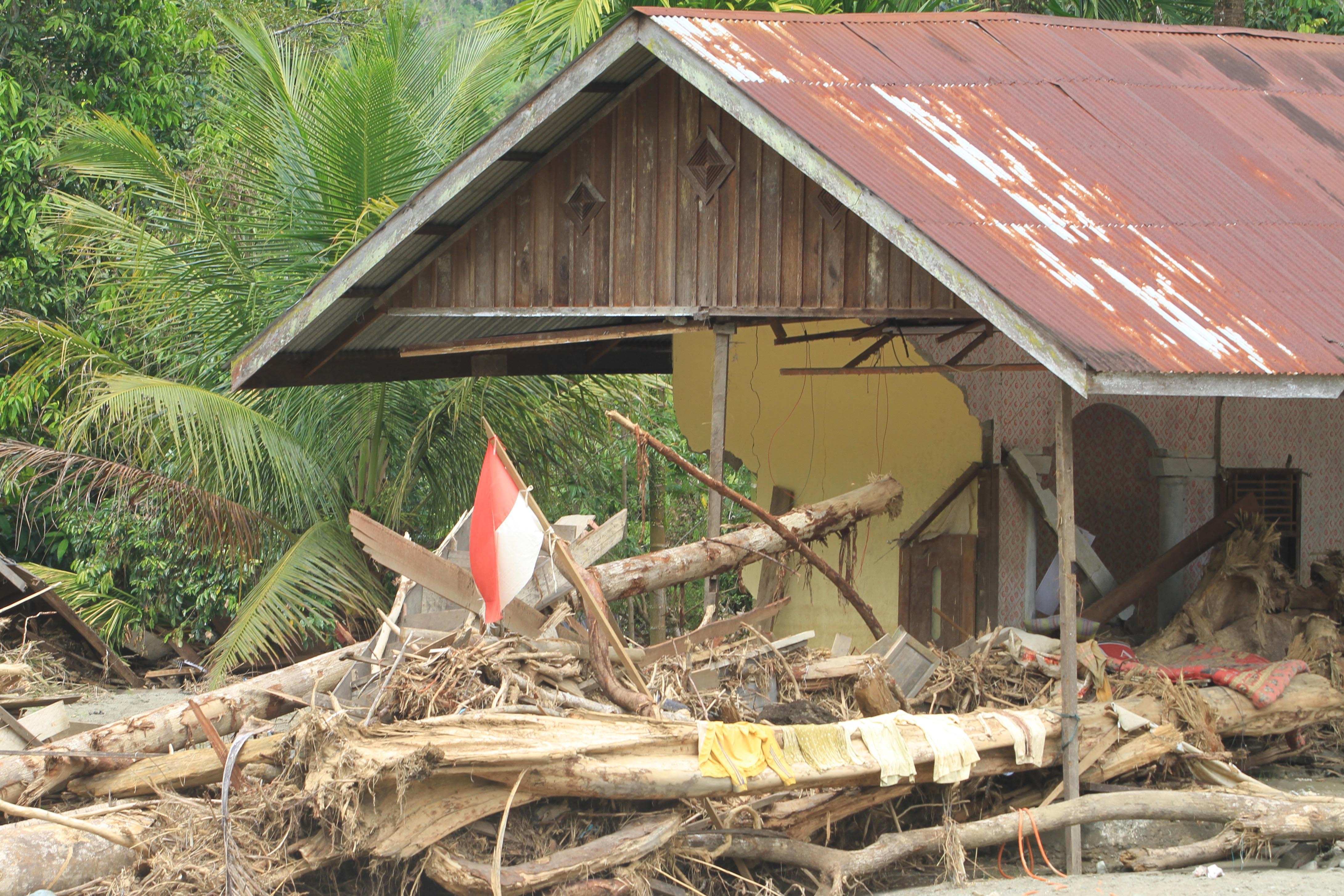 Bendera merah putih berkibar di depan rumah yang hancur diterjang banjir bandang di Desa Kuta Teugoh, Beutong Ateuh Banggalang, Nagan Raya, Aceh, Kamis (11/12/2025). Pemerintah Aceh memperpanjang status tanggap darurat bencana hidrometeorologi hingga 25 Desember dengan pertimbangan kondisi daerah yang membutuhkan penanganan secara intensif, terpadu, terintegrasi. 