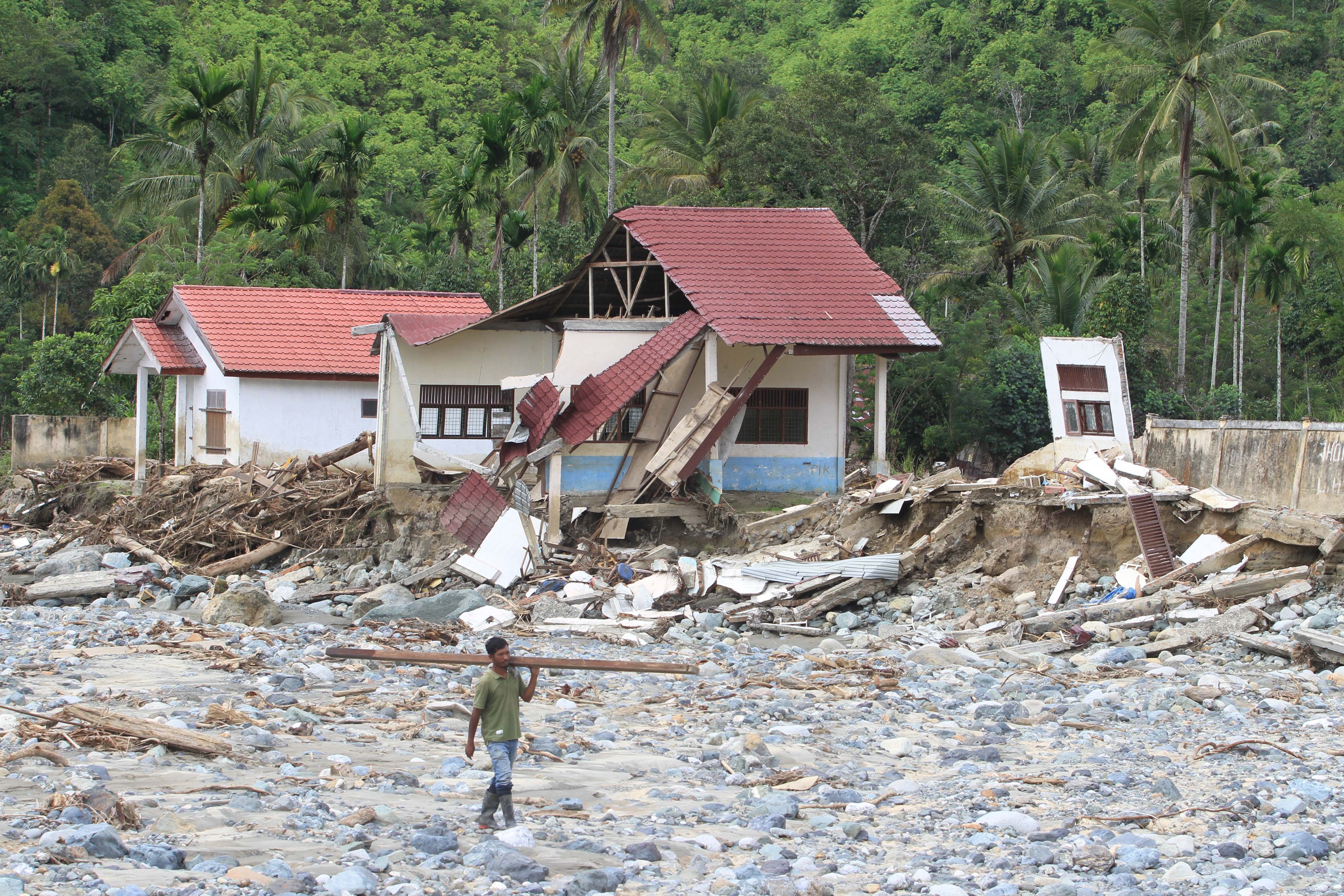 Warga melintas di dekat gedung Sekolah Dasar Negeri (SDN) 1 Beutong Ateuh Banggalang yang rusak karena diterjang banjir bandang di Kuta Teugong, Nagan Raya, Aceh, Kamis (11/12/2025). Berdasarkan data Dinas Pendidikan Kabupaten Nagan Raya sebanyak 23 unit gedung sekolah mengalami kerusakan yang tersebar Kecamatan Beutong Ateuh Banggalang, Tripa Makmur, Darul Makmur dan Kecamatan Tadu Raya dengan estimasi kerugian mencapai Rp43 miliar. 