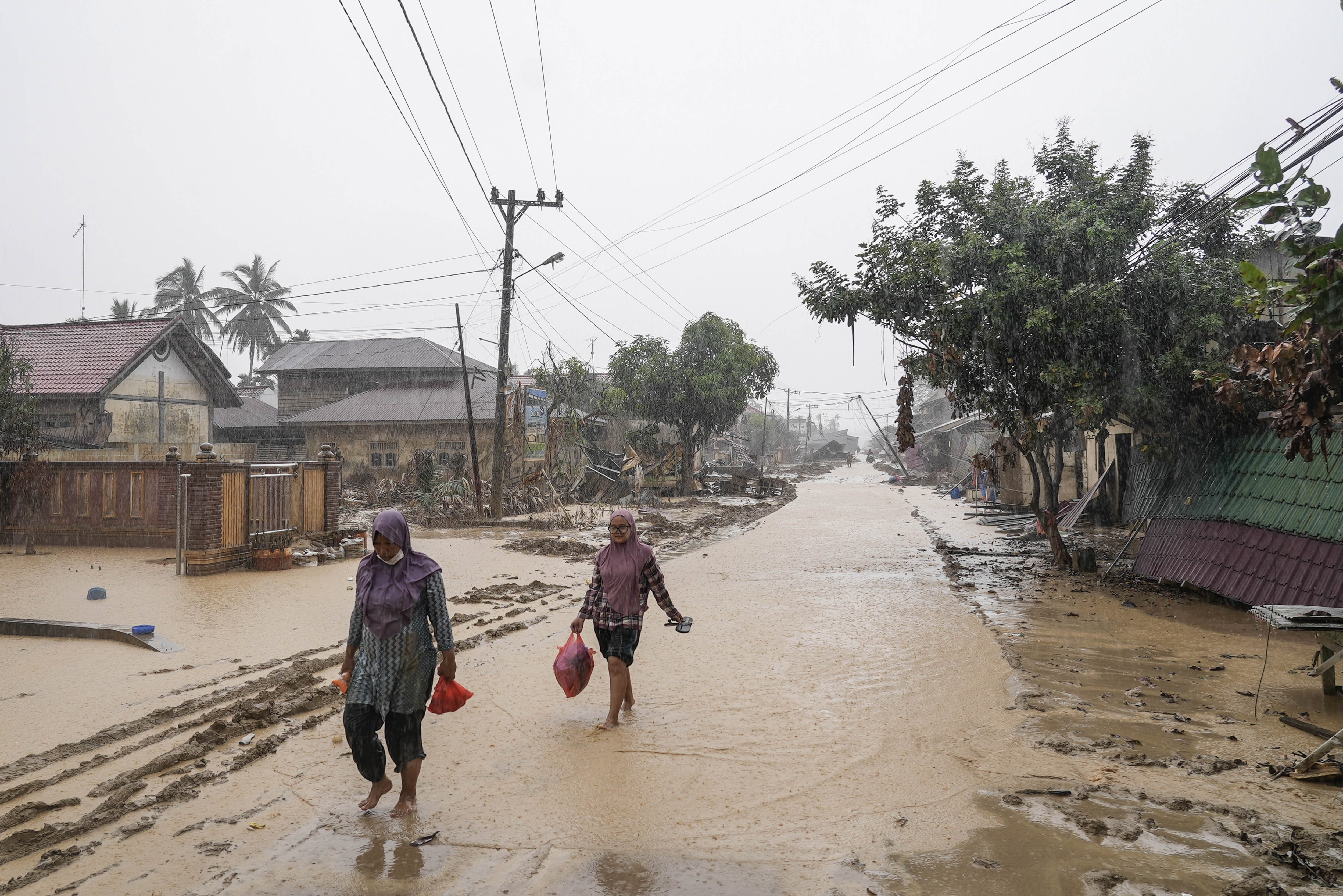 Warga berjalan di desa yang luluh lantak pascabanjir di Desa Bundar, Karang Baru, Kabupaten Aceh Tamiang, Aceh, Selasa (9/12/2025). Badan Nasional Penanggulangan Bencana (BNPB) mencatat per Selasa (9/12) sebanyak 964 orang meninggal dan 264 jiwa belum ditemukan dengan rincian 31 jiwa masih hilang di Aceh, 138 jiwa hilang di Sumatera Utara, dan 95 hilang di Sumatera Barat.