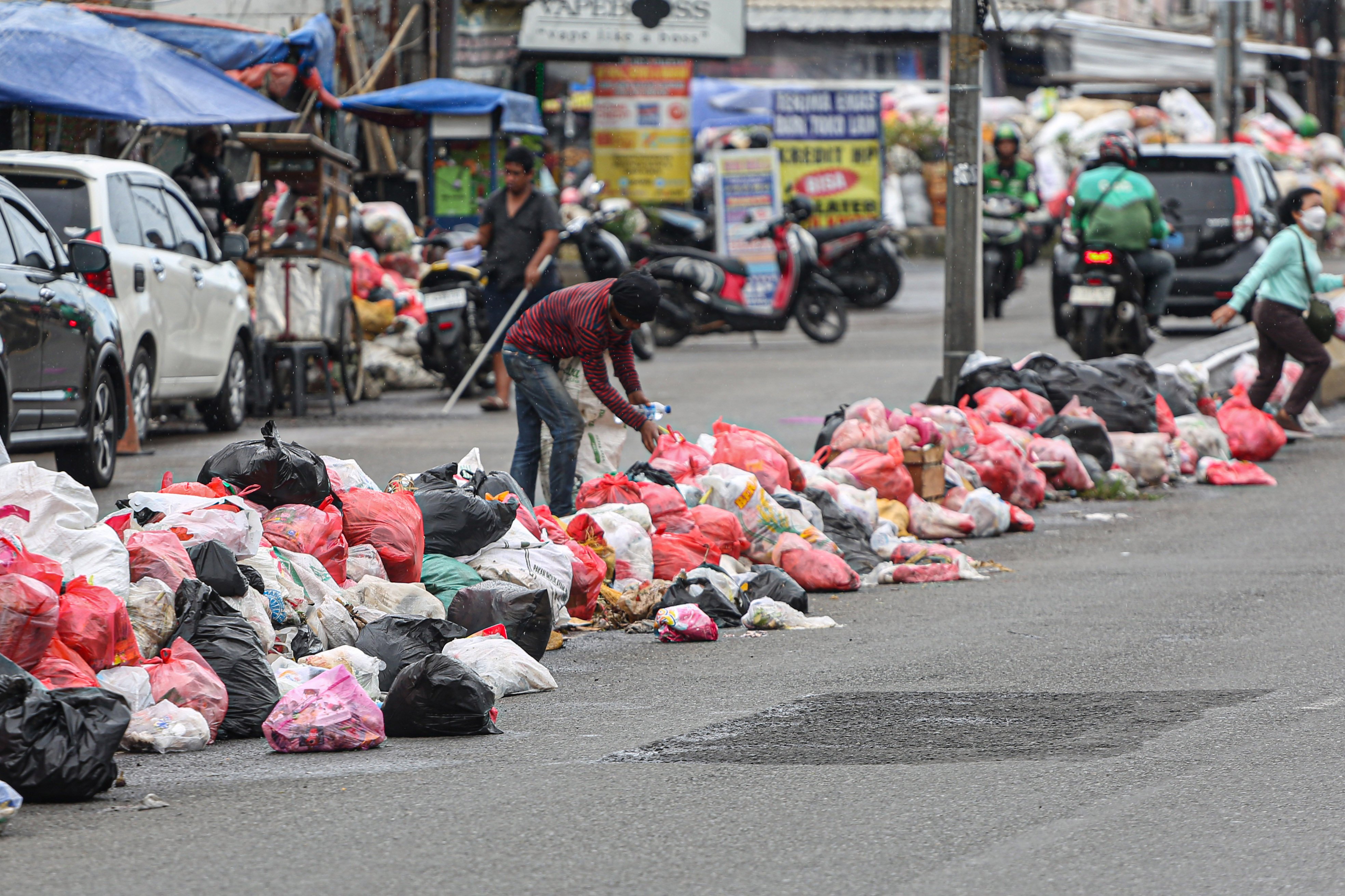 Pemulung memungut sampah yang menumpuk di Jalan Dewi Sartika, Ciputat, Kota Tangerang Selatan, Banten, Rabu (17/12/2025). Tumpukan sampah itu terjadi setelah Tempat Pembuangan Akhir (TPA) Cipeucang ditutup sementara dalam rangka perbaikan.
