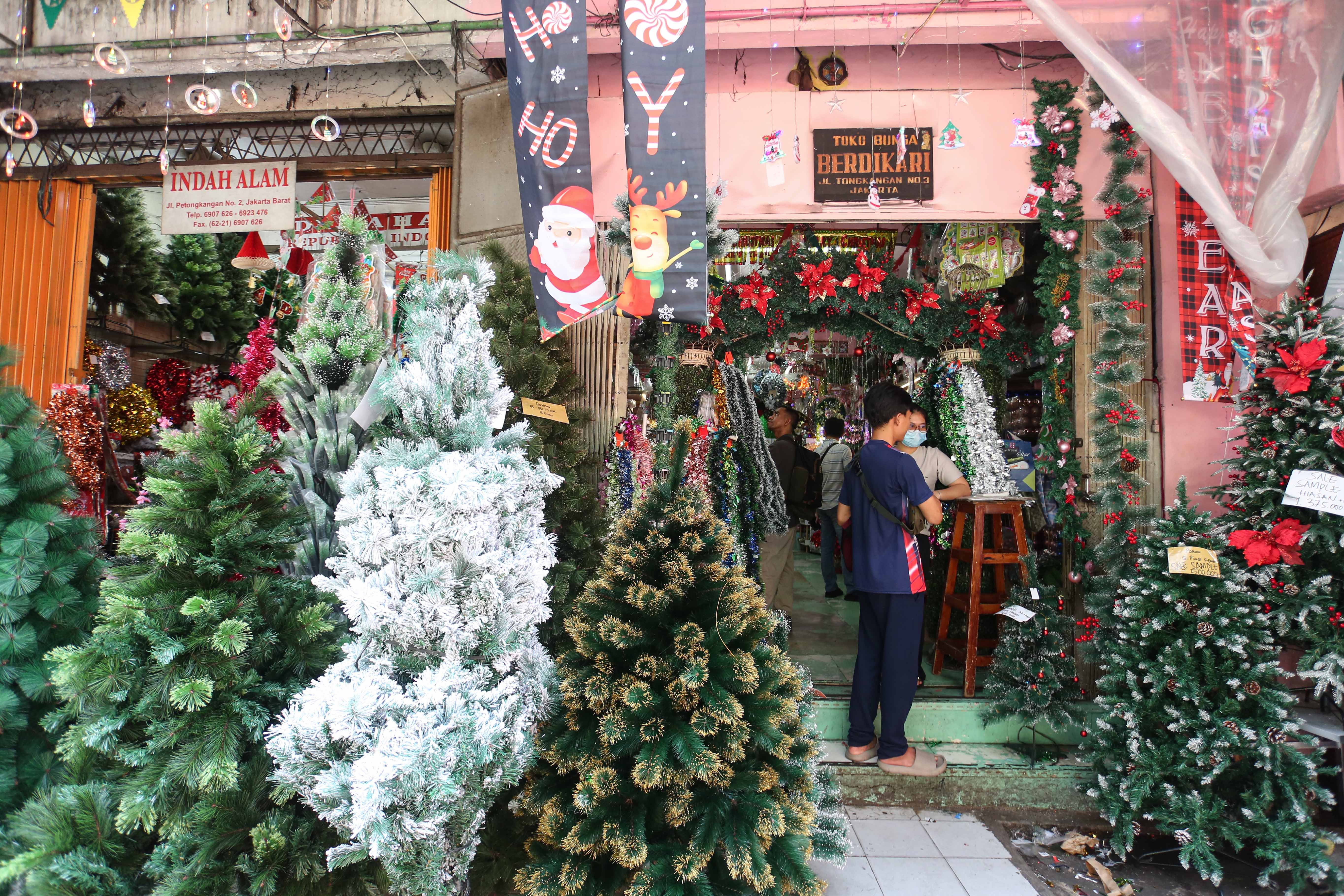 Calon pembeli melihat hiasan Natal yang dijual di salah satu toko di Pasar Asemka, Jakarta Barat, Senin (22/12/2025). Dekorasi bertemakan Natal seperti lonceng, pita, lampu bintang, topi, pohon Natal hingga hiasan figur rusa, boneka salju dan sinterklas tersebut dijual dengan harga mulai dari Rp.5.000 hingga Rp10 juta per buah.