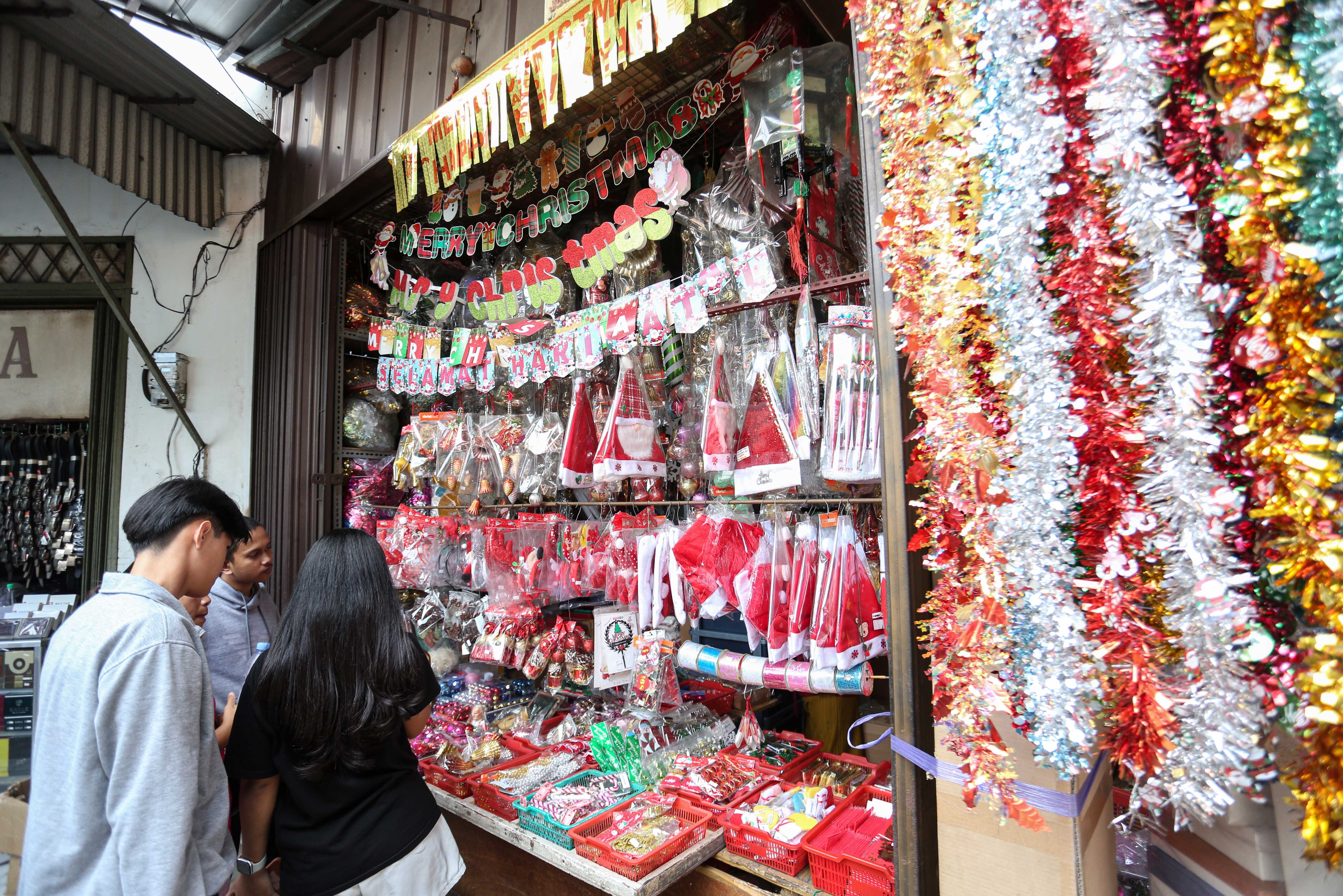 Calon pembeli melihat hiasan Natal yang dijual di salah satu toko di Pasar Asemka, Jakarta Barat, Senin (22/12/2025). Dekorasi bertemakan Natal seperti lonceng, pita, lampu bintang, topi, pohon Natal hingga hiasan figur rusa, boneka salju dan sinterklas tersebut dijual dengan harga mulai dari Rp.5.000 hingga Rp10 juta per buah.