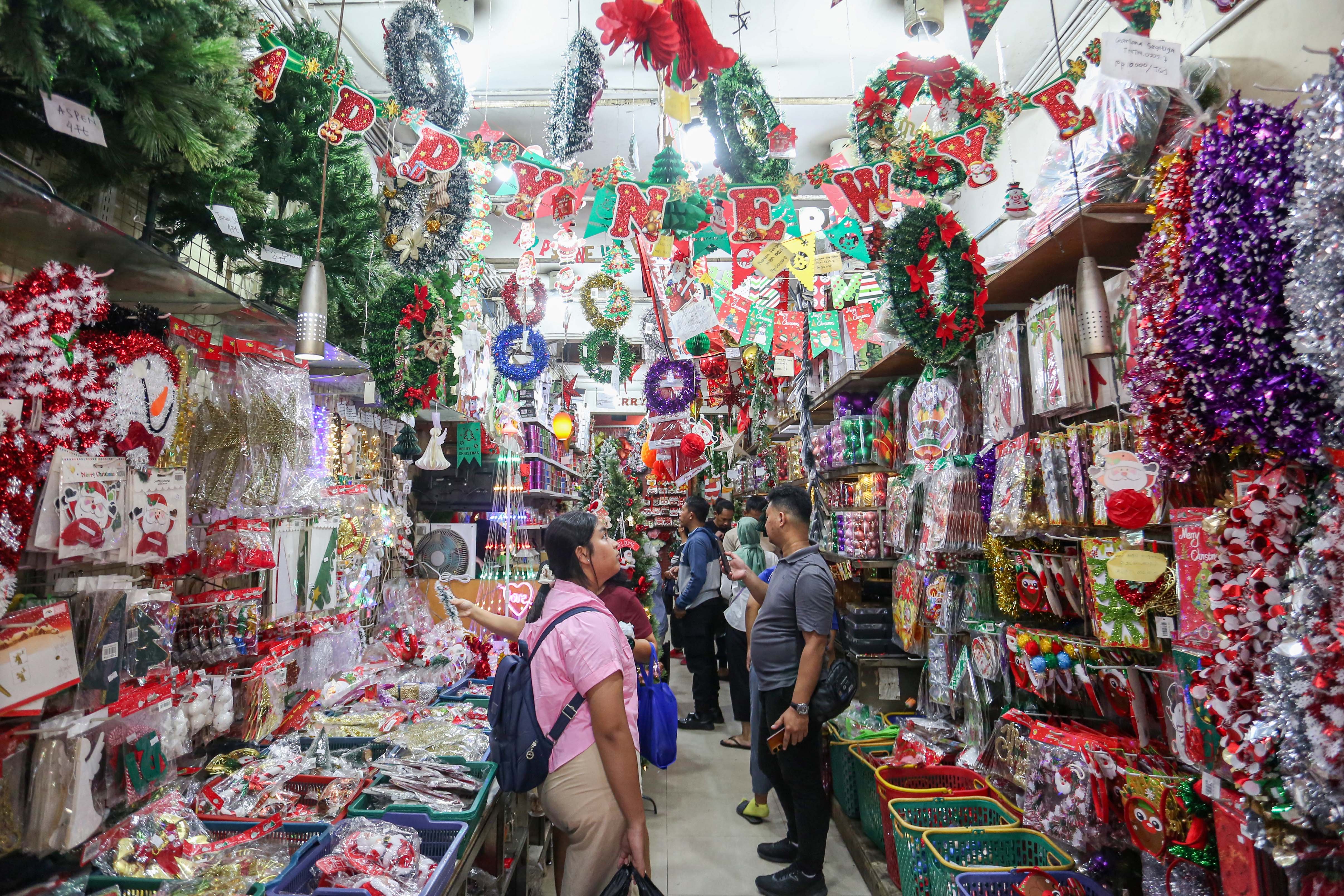Calon pembeli melihat hiasan Natal yang dijual di salah satu toko di Pasar Asemka, Jakarta Barat, Senin (22/12/2025). Dekorasi bertemakan Natal seperti lonceng, pita, lampu bintang, topi, pohon Natal hingga hiasan figur rusa, boneka salju dan sinterklas tersebut dijual dengan harga mulai dari Rp.5.000 hingga Rp10 juta per buah.