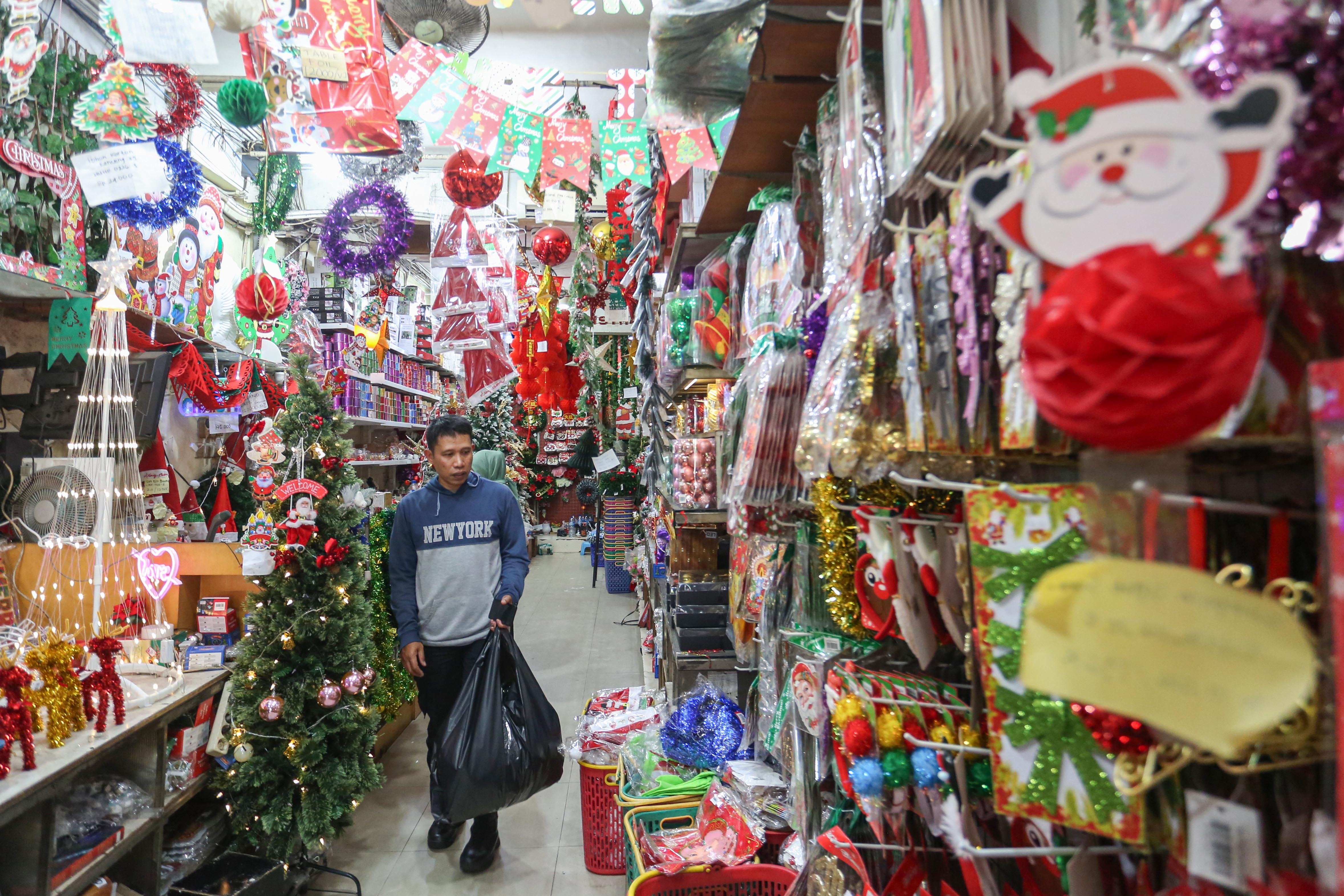 Calon pembeli melihat hiasan Natal yang dijual di salah satu toko di Pasar Asemka, Jakarta Barat, Senin (22/12/2025). Dekorasi bertemakan Natal seperti lonceng, pita, lampu bintang, topi, pohon Natal hingga hiasan figur rusa, boneka salju dan sinterklas tersebut dijual dengan harga mulai dari Rp.5.000 hingga Rp10 juta per buah.