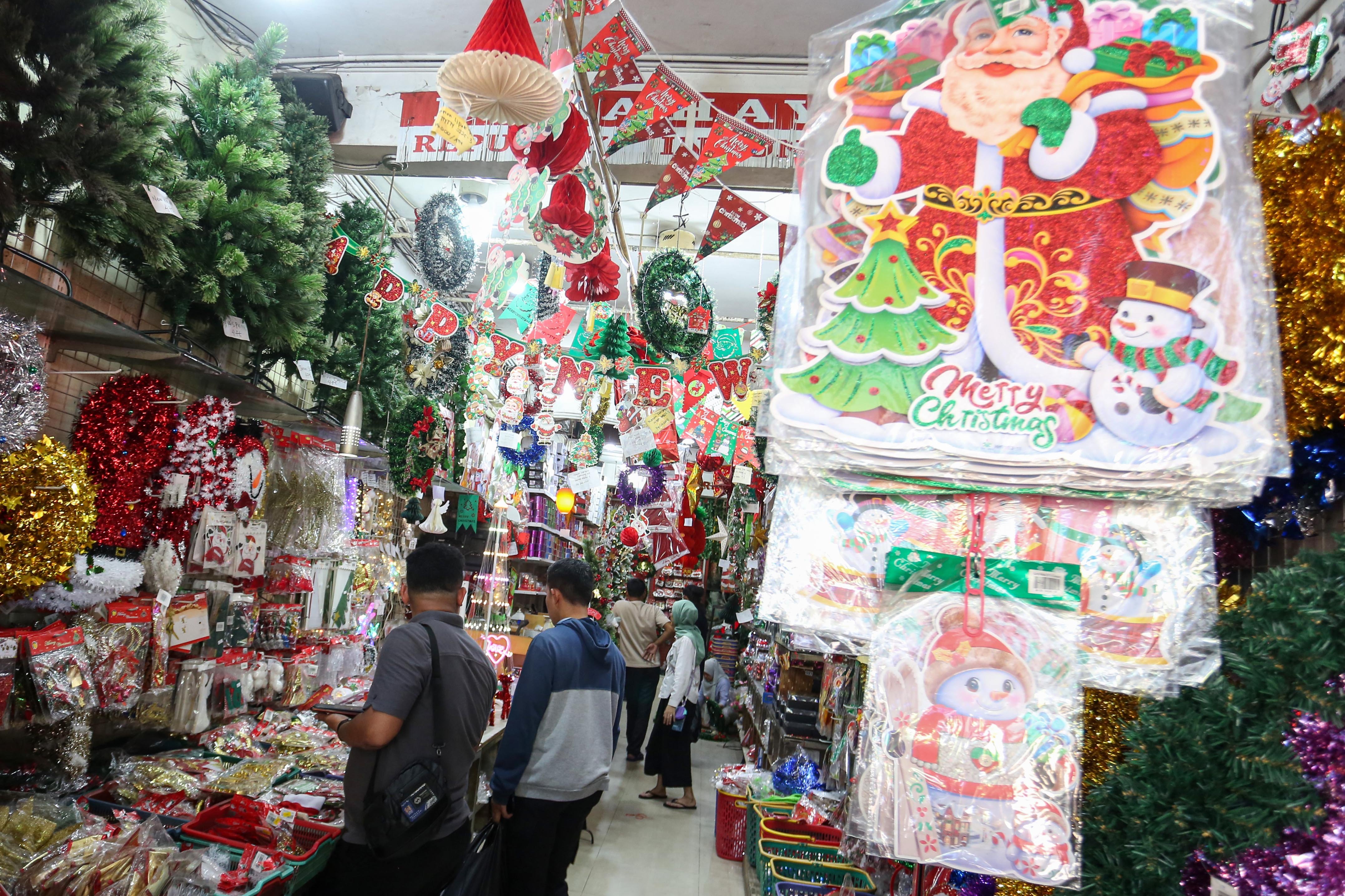 Calon pembeli melihat hiasan Natal yang dijual di salah satu toko di Pasar Asemka, Jakarta Barat, Senin (22/12/2025). Dekorasi bertemakan Natal seperti lonceng, pita, lampu bintang, topi, pohon Natal hingga hiasan figur rusa, boneka salju dan sinterklas tersebut dijual dengan harga mulai dari Rp.5.000 hingga Rp10 juta per buah.