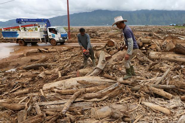 Warga memotong batang kayu yang terbawa tanah longsor saat pembersihan lahan dan pemukiman di Toweran Uken, Lut Tawar, Aceh Tengah, Aceh, Jumat (2/1/2026). Bencana banjir dan tanah longsor yang terjadi akhir November 2025 di pemukiman pinggir Danau Laut Tawar itu telah mengakibatkan 115 unit rumah rusak dan 700 kepala keluarga mengungsi serta llahan pertanian tertimbun lumpur dan batang kayu.