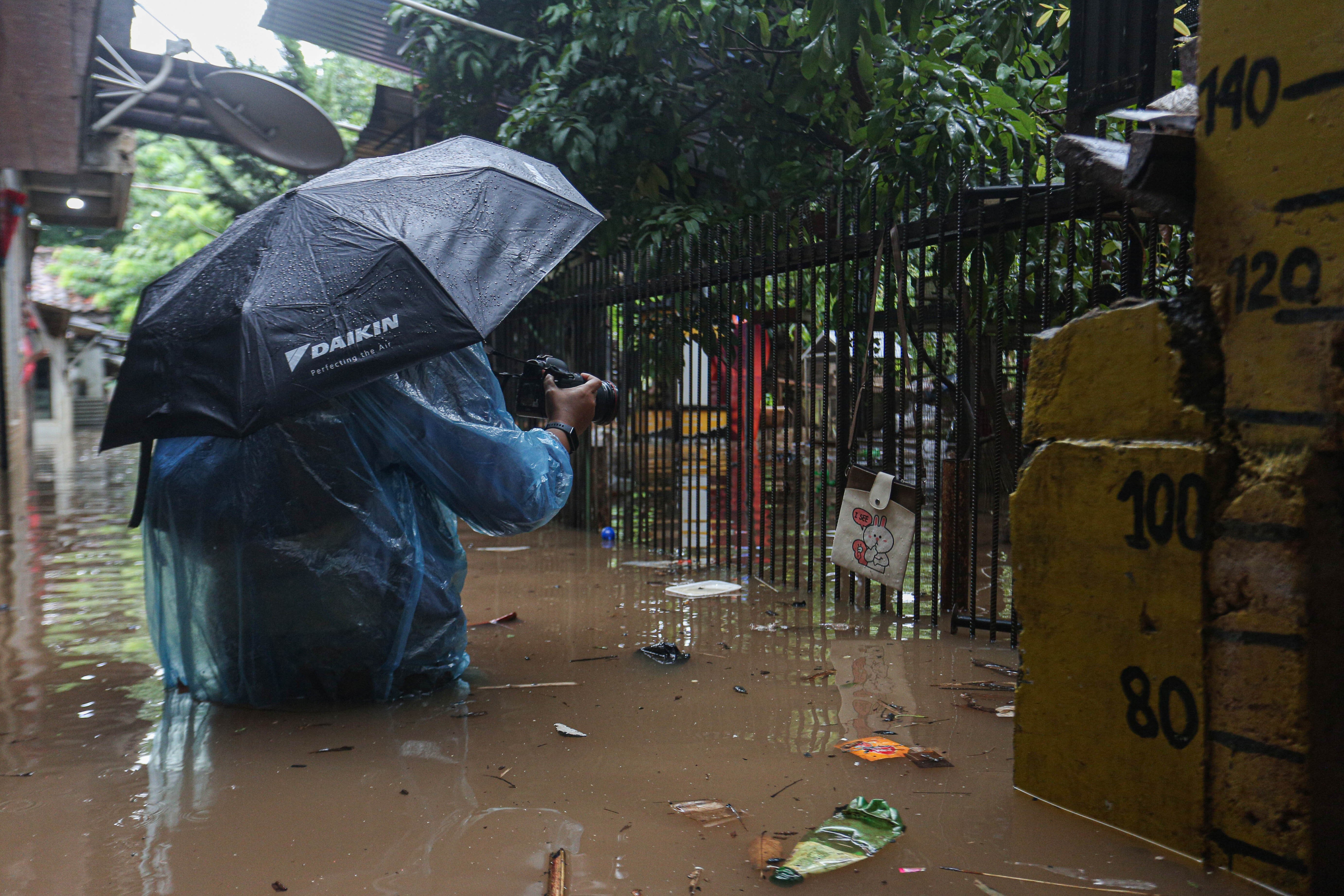Wartawan mengambil gambar rumah warga yang terendam banjir wilayah Cilandak Timur, Kecamatan Pasar Minggu, Jakarta Selatan, Senin (12/1/2026). Banjir setinggi 20-70 sentimeter yang menggenangi kawasan tersebut disebabkan oleh curah hujan tinggi dan meluapnya Kali Krukut.