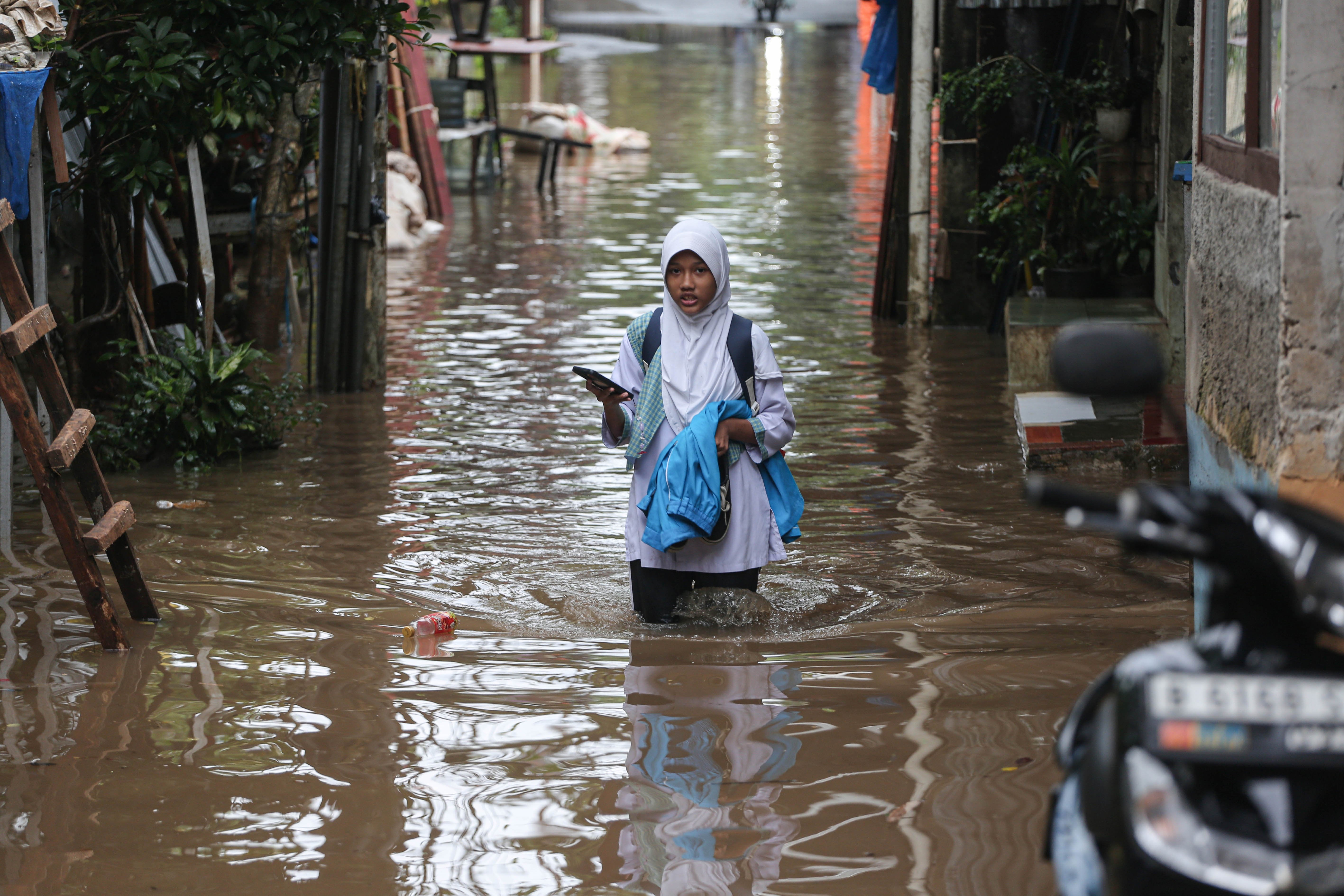 Siswa sekolah berjalan melintasi banjir yang merendam wilayah Cilandak Timur, Kecamatan Pasar Minggu, Jakarta Selatan, Senin (12/1/2026). Banjir setinggi 20-70 sentimeter yang menggenangi kawasan tersebut disebabkan oleh curah hujan tinggi dan meluapnya Kali Krukut.
