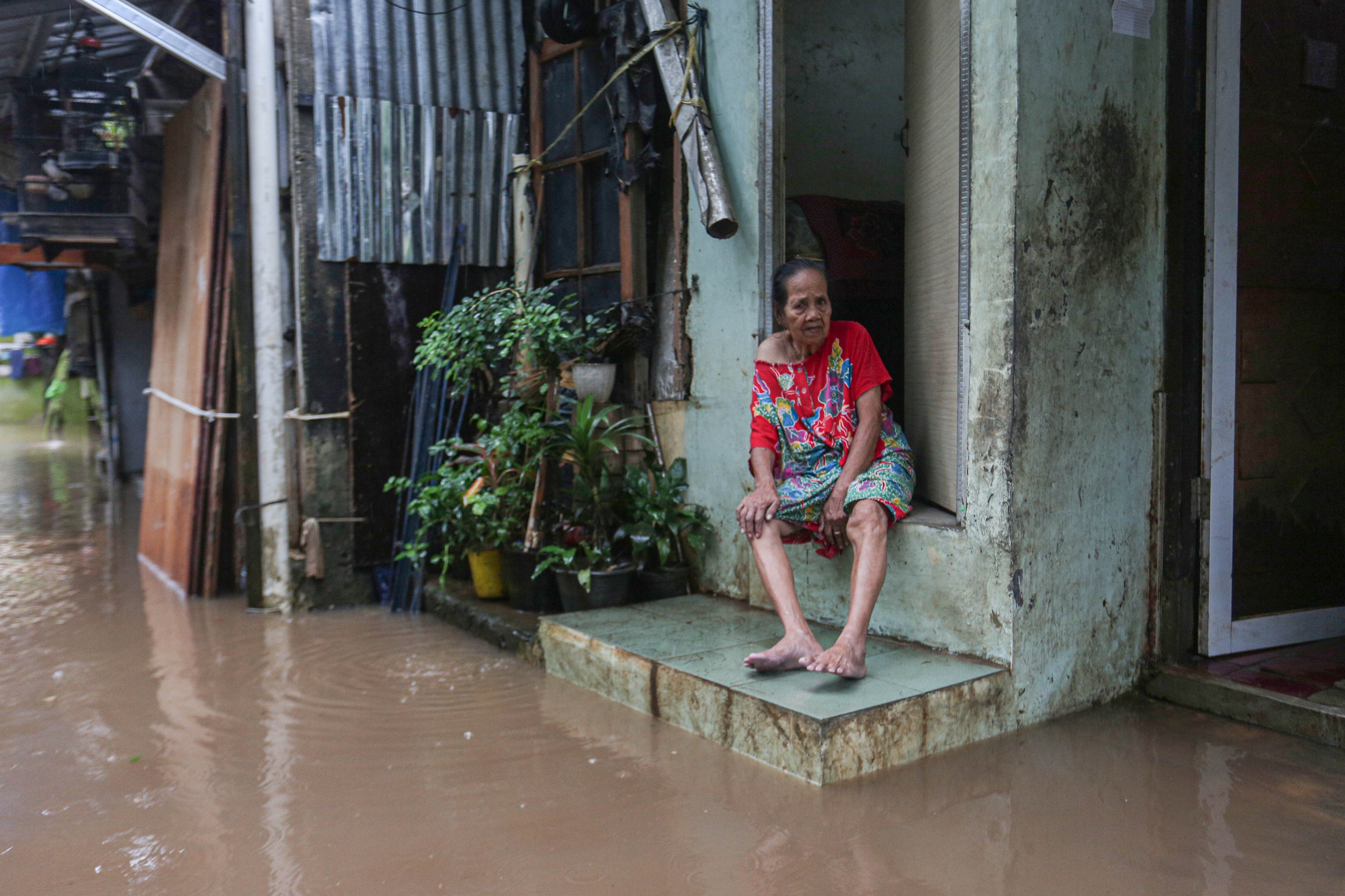 Warga duduk di depan rumahnya yang terendam banjir di wilayah Cilandak Timur, Kecamatan Pasar Minggu, Jakarta Selatan, Senin (12/1/2026). Banjir setinggi 20-70 sentimeter yang menggenangi kawasan tersebut disebabkan oleh curah hujan tinggi dan meluapnya Kali Krukut.