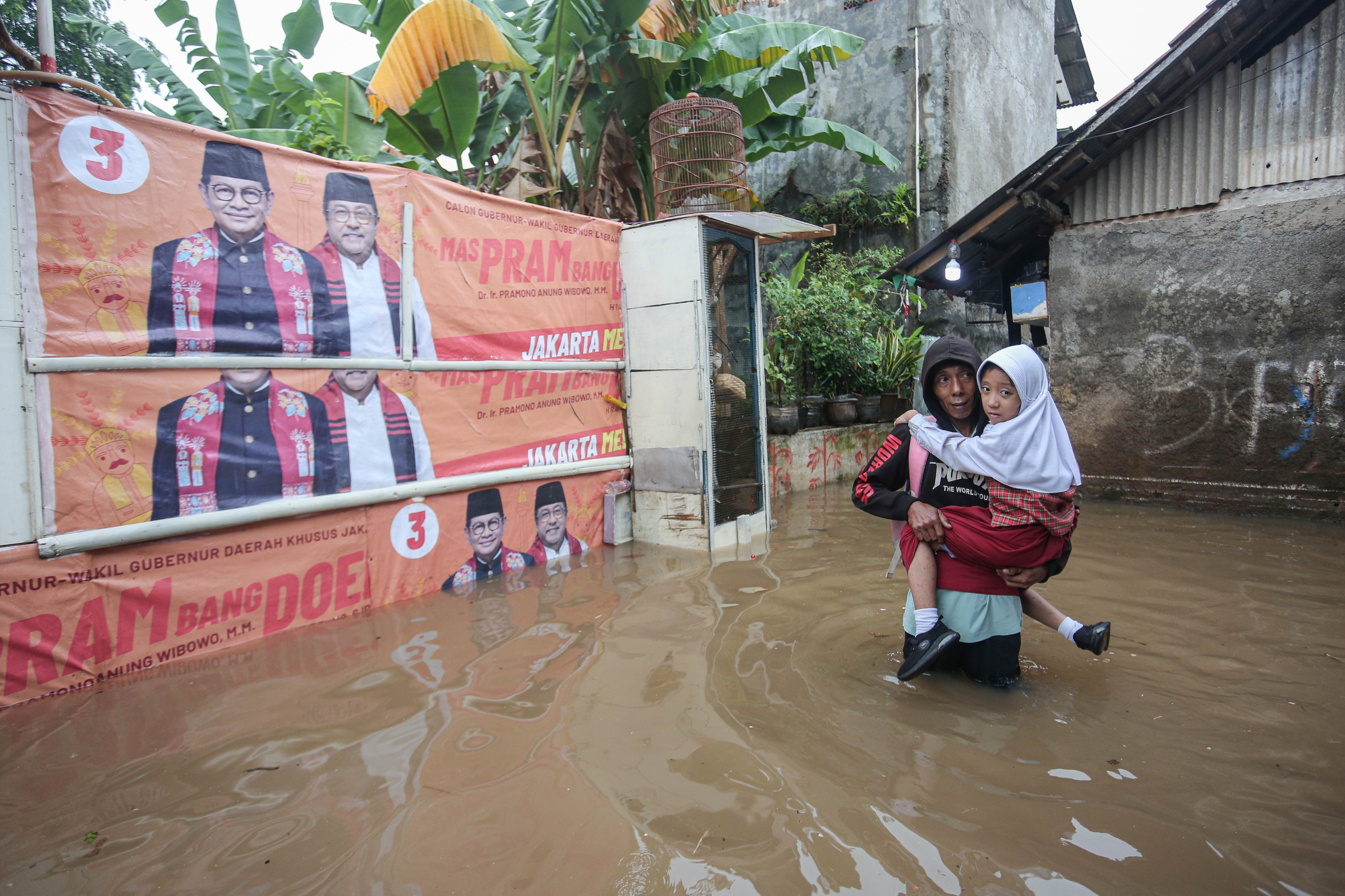 Warga menggendong anaknya saat melintasi banjir yang merendam wilayah Cilandak Timur, Kecamatan Pasar Minggu, Jakarta Selatan, Senin (12/1/2026). Banjir setinggi 20-70 sentimeter yang menggenangi kawasan tersebut disebabkan oleh curah hujan tinggi dan meluapnya Kali Krukut.