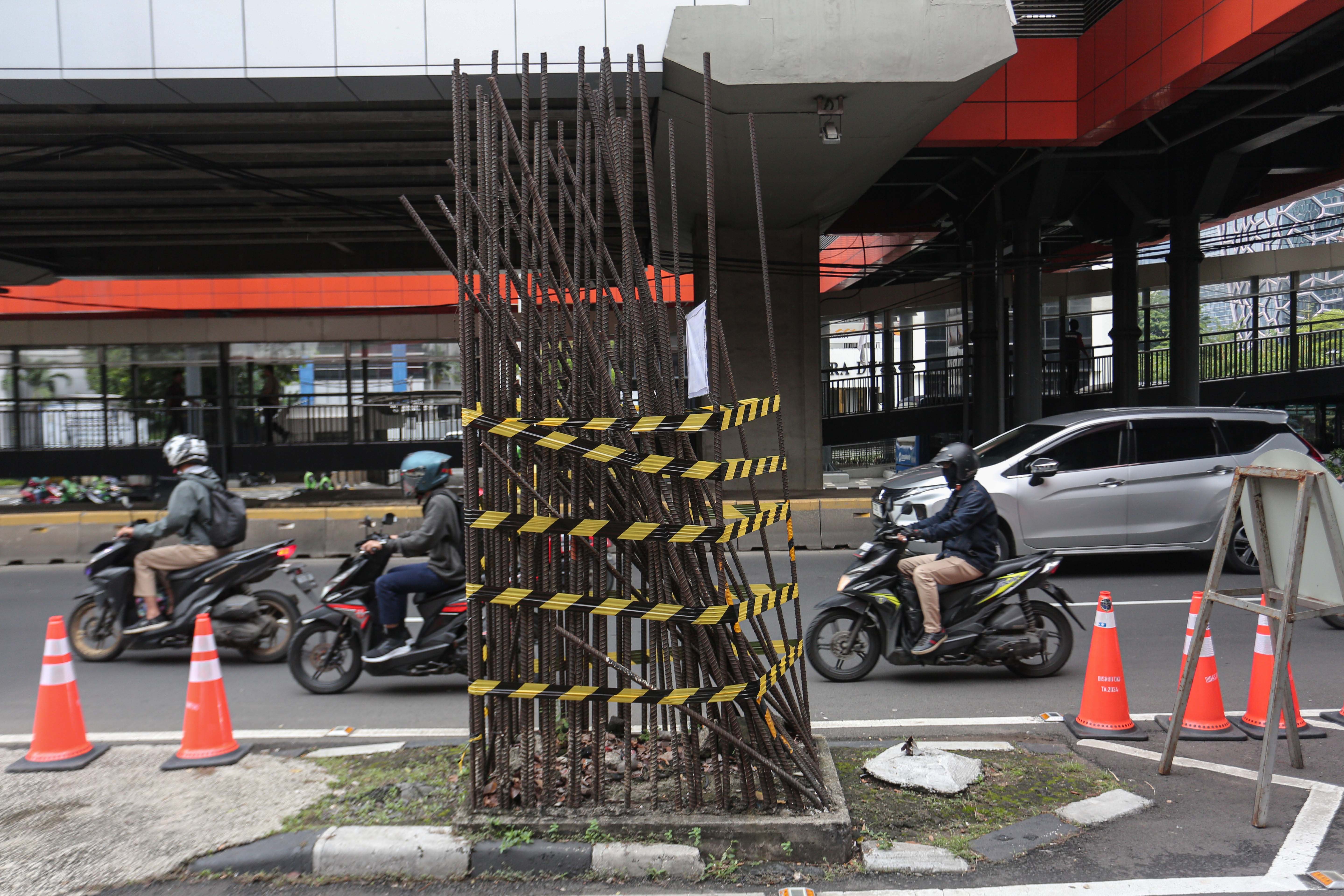 Pengendara sepeda motor melintas di dekat tiang monorel yang akan dibongkar di Jalan H.R. Rasuna Said, Kuningan, Jakarta Selatan, Rabu (14/1/2026). Pemerintah Provinsi DKI Jakarta mulai membongkar 109 tiang monorel yang mangkrak dan akan menata pedestrian di kawasan Rasuna Said dengan mengalokasikan anggaran Rp102 miliar.