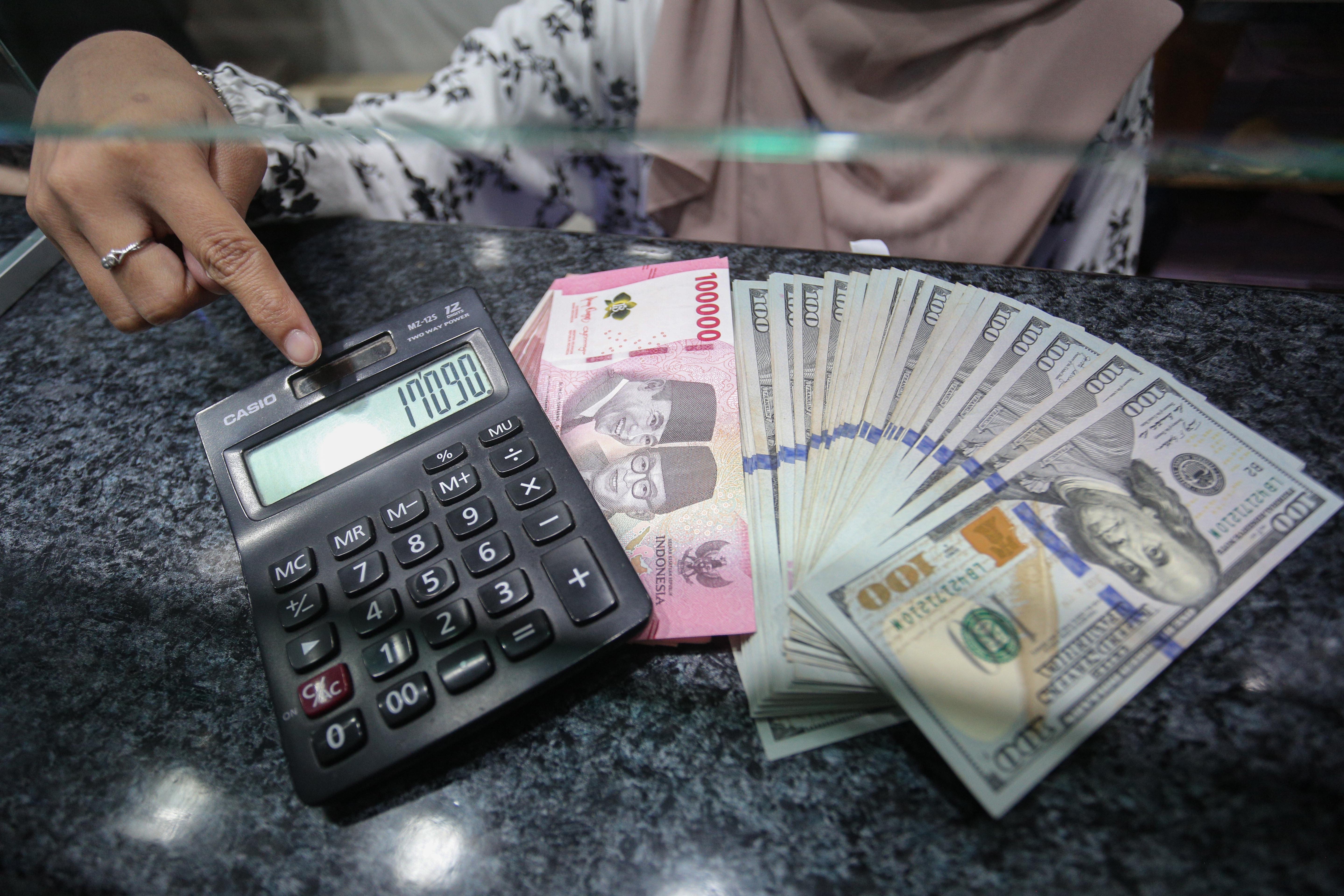Petugas menunjukkan pecahan mata uang rupiah dan dolar Amerika Serikat (AS) di gerai penukaran uang asing di Jakarta, Rabu (21/1/2026). Nilai tukar rupiah rupiah perlahan bergerak menguat 20 poin menjadi Rp16.936 per dolar AS dari sebelumnya Rp16.956 per dolar AS pada penutupan perdagangan.