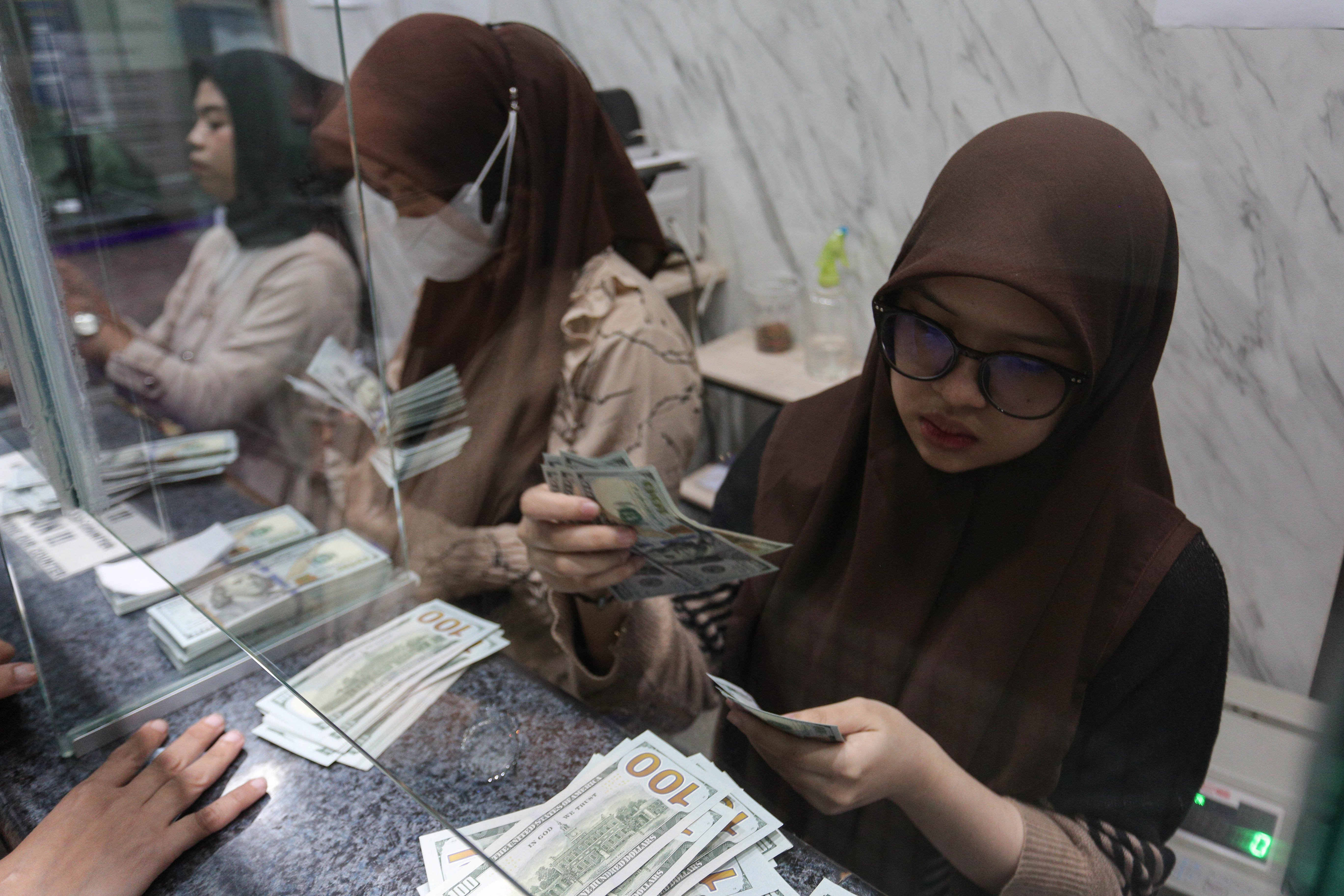 Petugas menghitung pecahan mata uang dolar Amerika Serikat (AS) di gerai penukaran uang asing di Jakarta, Rabu (21/1/2026). Nilai tukar rupiah rupiah perlahan bergerak menguat 20 poin menjadi Rp16.936 per dolar AS dari sebelumnya Rp16.956 per dolar AS pada penutupan perdagangan.